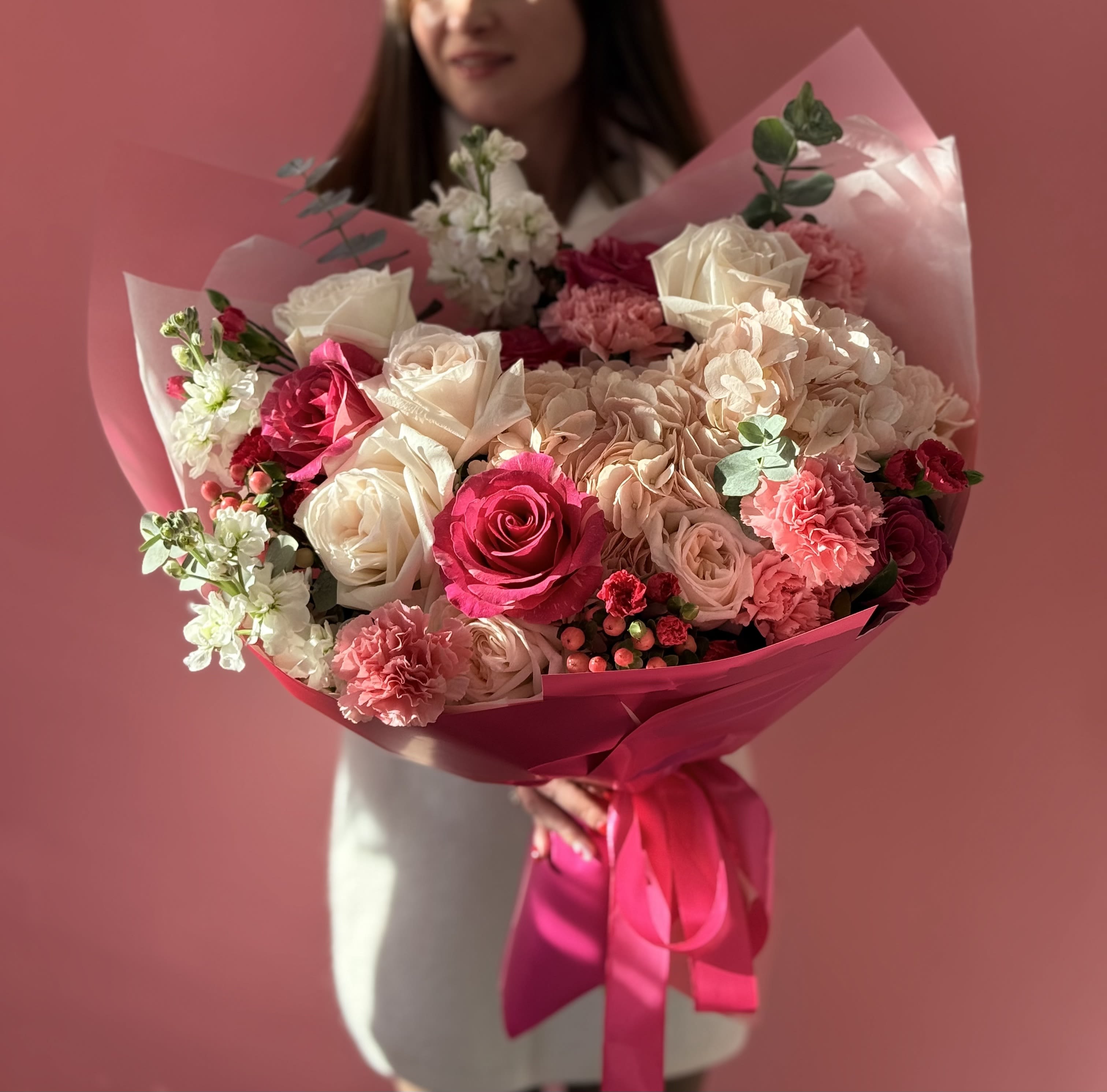 Bouquet of pink and white roses with carnations wrapped in pink paper