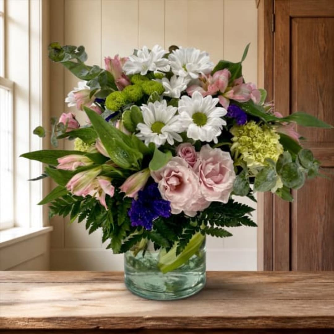 Mixed bouquet of white daisies and pink roses in a glass vase