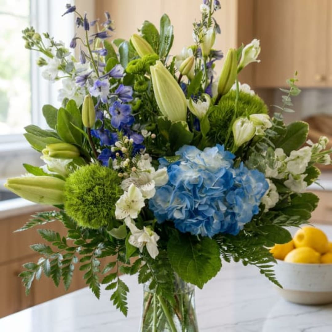 Blue hydrangea and white lily bouquet in a glass vase