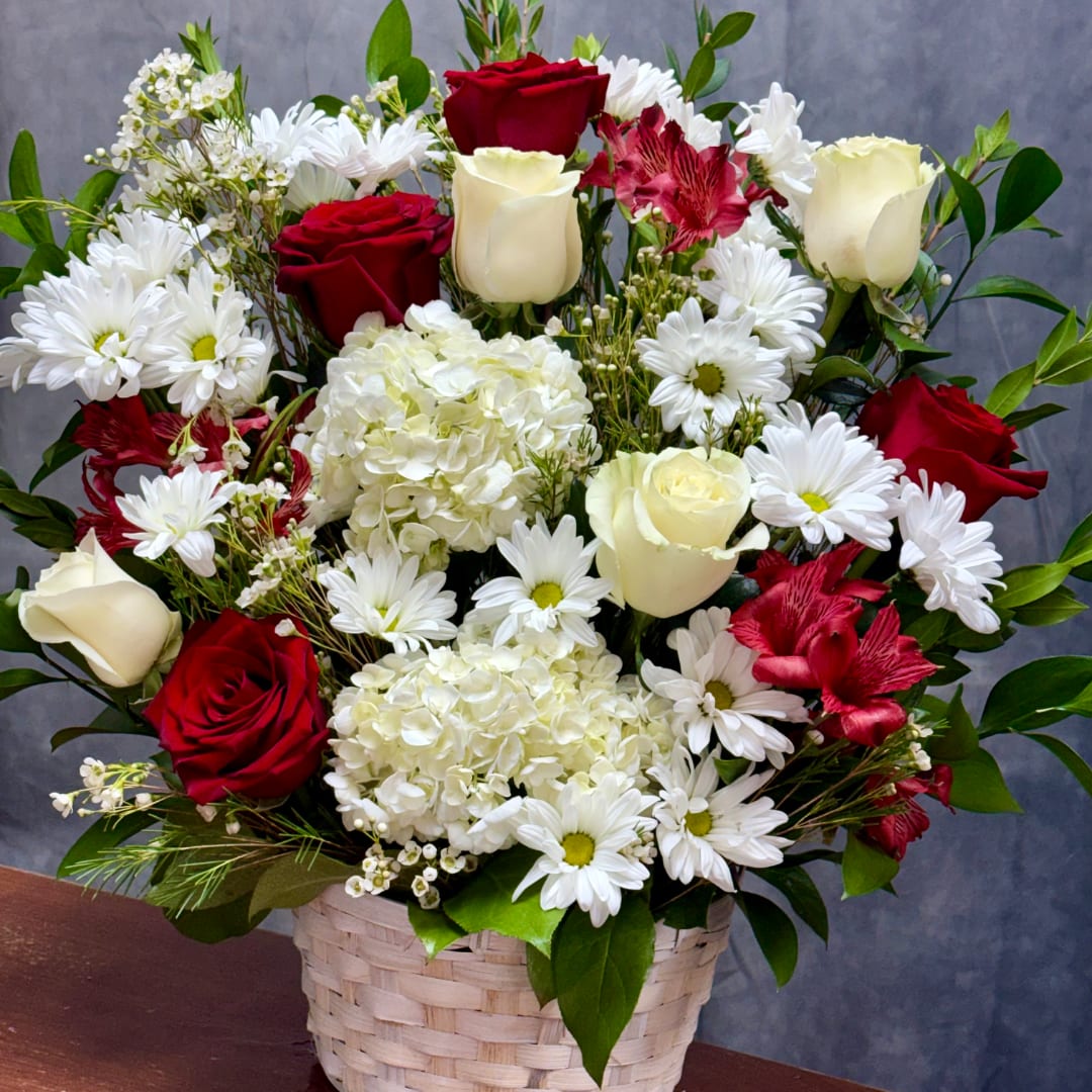 Basket arrangement of red and white roses, daisies, and hydrangeas