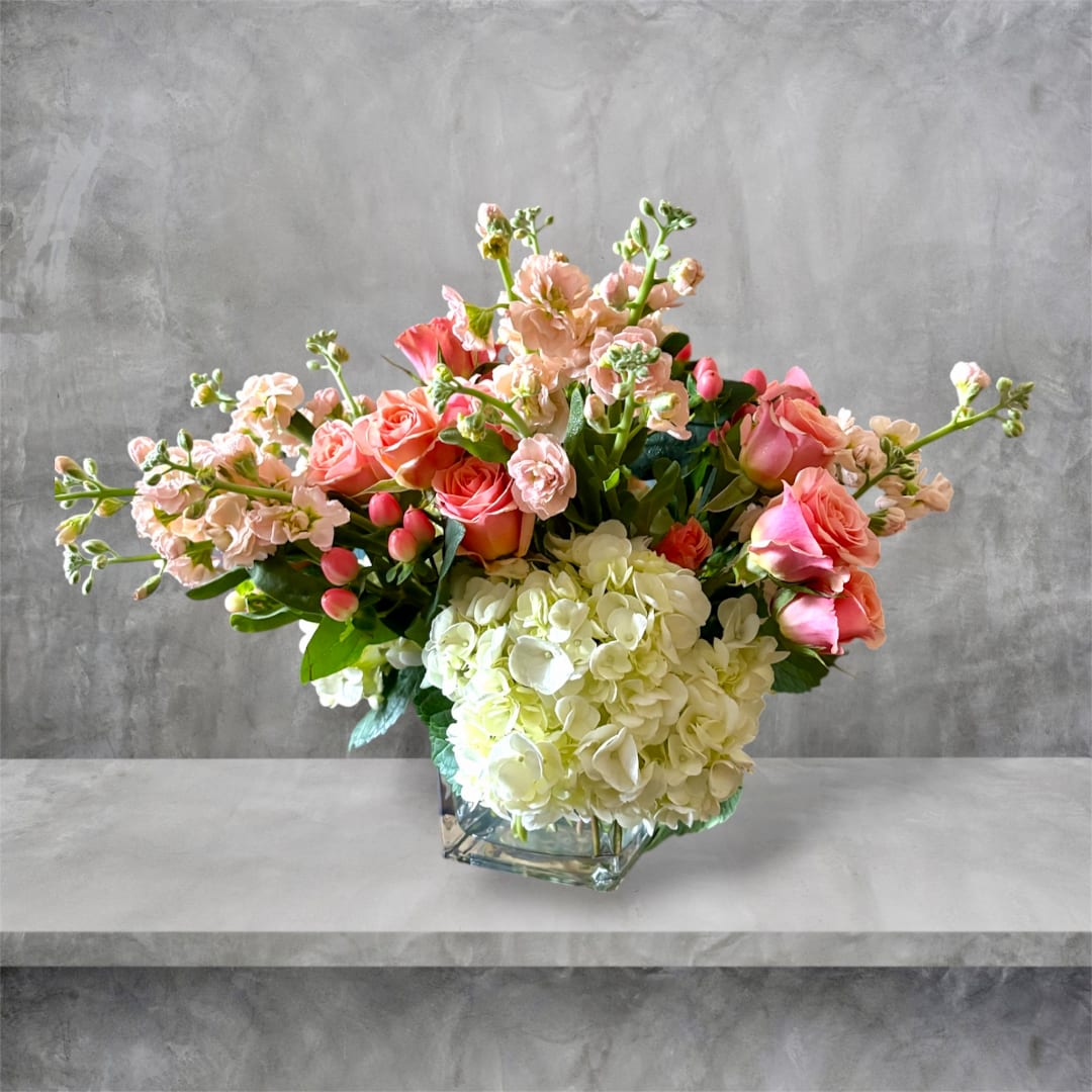 Pink roses and white hydrangeas arranged in a glass vase