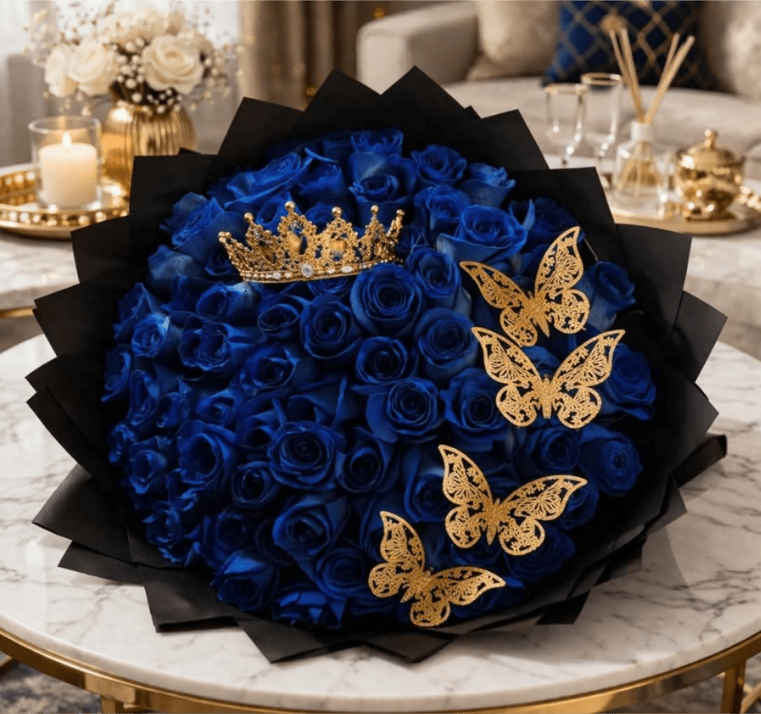Royal Blue Rose Bouquet With Gold Crown and Butterflies - A dramatic crown of vivid royal-blue roses gives this flower arrangement a regal, celebratory presence - perfect as a birthday bouquet, anniversary roses, or a show-stopping gift to make someone feel honored. The bold mix of deep blue blooms against layered black wrapping reads luxurious and stylized; the recipient will feel uniquely celebrated the moment they see it.  Densely packed blue roses form the heart of the design, surrounded by layered black paper for high-contrast drama. Gold butterfly ornaments and a jeweled gold crown are placed across the front and near the top, adding metallic sparkle and a decorative, couture finish. The piece leans decorative rather than naturalistic, ideal for gifting at milestone moments or as an elegant event display.  This arrangement suits anyone who appreciates bold color and theatrical styling - send it to mark a special birthday, an anniversary, or to say "you're extraordinary" in unmistakable fashion. Care is simple: keep the stems hydrated and away from direct heat to preserve the vivid color and crafted accents.