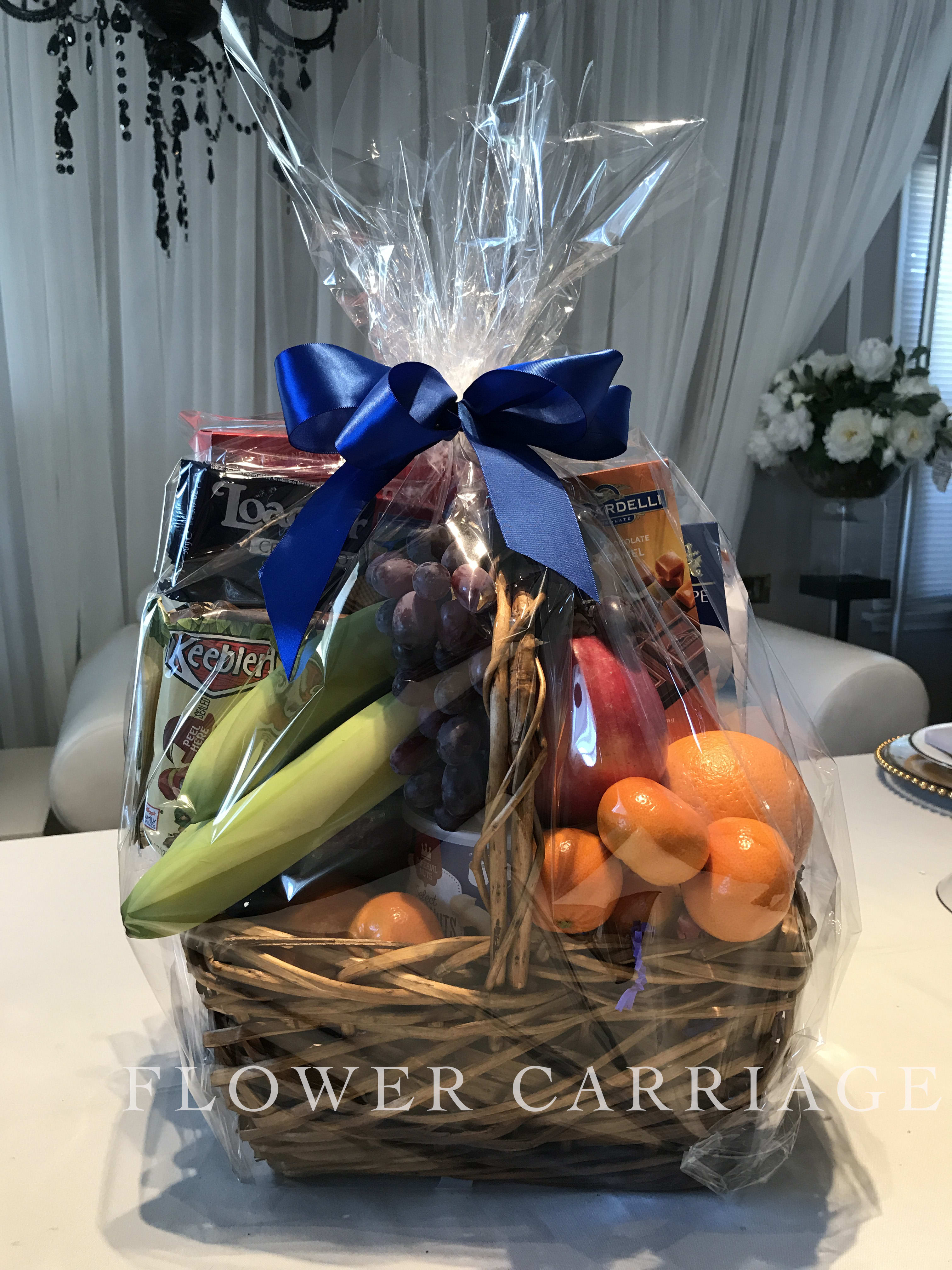 Gift basket with fruit, snacks, and a blue ribbon