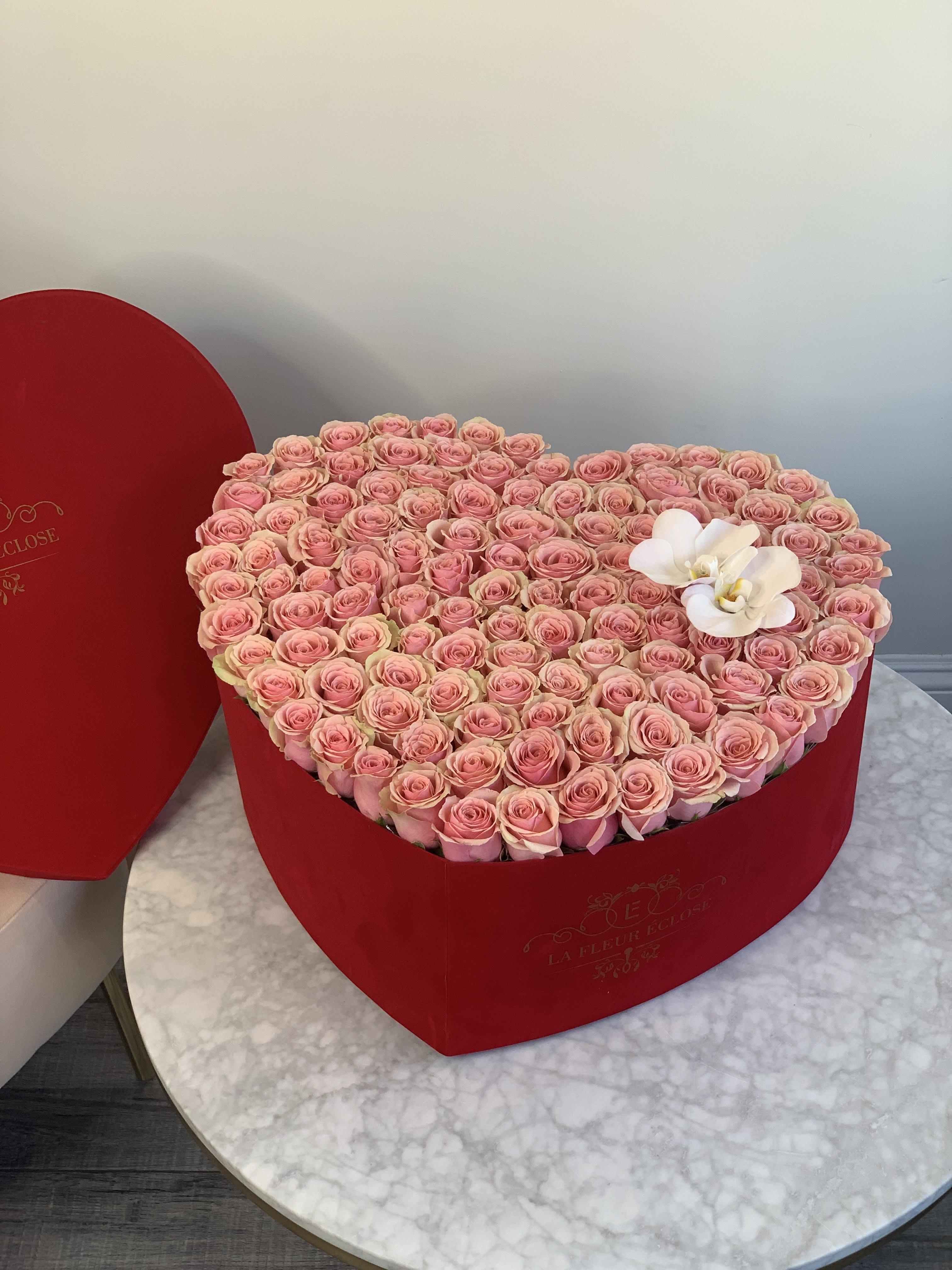 Heart-shaped box filled with pink roses and white orchids