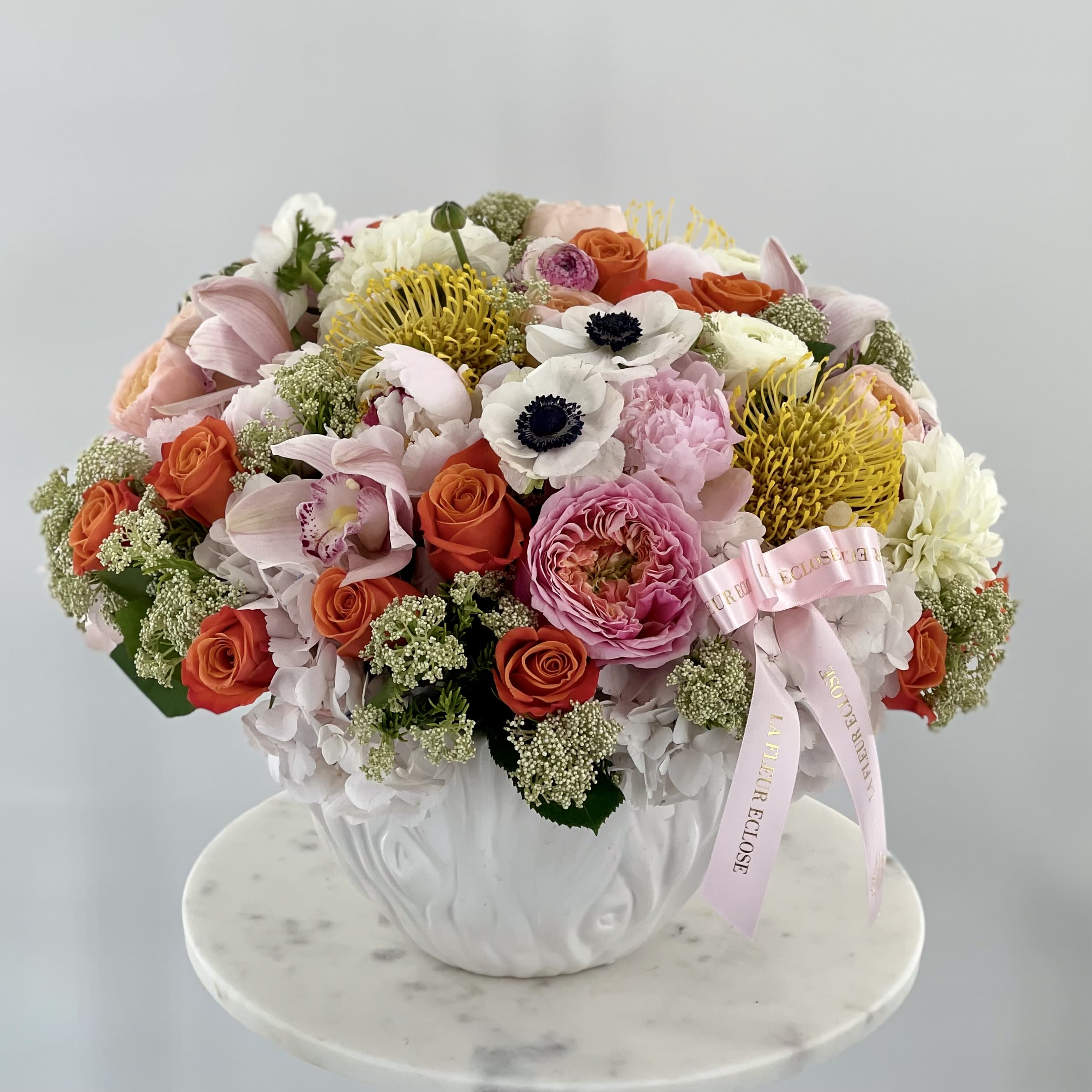 Mixed bouquet in a white vase with pink, orange, yellow, and white flowers
