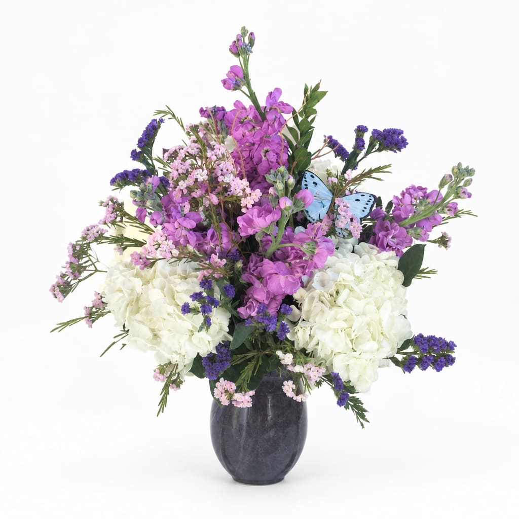 Purple and white flower arrangement in a dark vase with a blue butterfly accent