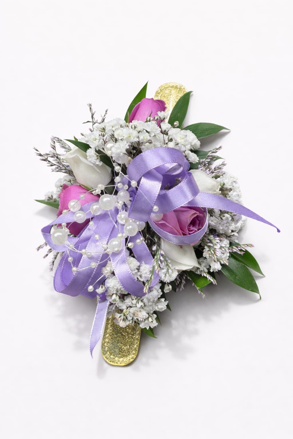 Lavender Pearl Wrist Corsage With Spray Roses for Wedding - Lavender and pink rosebuds cluster into a soft, romantic wrist corsage perfect for a wedding - the Lavender Pearl Wrist Corsage With Spray Roses gives the person you're celebrating a quietly elegant moment of attention. Layered loops of lavender satin ribbon and strands of pearl bead accents catch the light against a gold glitter wrist corsage band, so she'll feel dressed up without overpowering her gown or bridesmaid dress.  This corsage features spray roses with pink and lavender tones, white mini calla-style blooms, and small white filler flowers that add texture and gentle height. The wide lavender satin ribbon is woven through the arrangement and paired with faux pearls for a classic, dressy finish; mounted on a sturdy gold glitter band, it's designed to sit comfortably on the wrist for the duration of the day. Dimensions and fit are crafted to suit formal events while remaining lightweight and wearable.  Ideal for brides, bridesmaids, mothers, or honored guests, this piece says "thoughtful and refined" - a meaningful accent for wedding ceremonies and receptions in Newington, CT and beyond. Order with confidence for a ceremony or rehearsal; light misting and keeping it cool before the event will help the fresh flowers look their best.