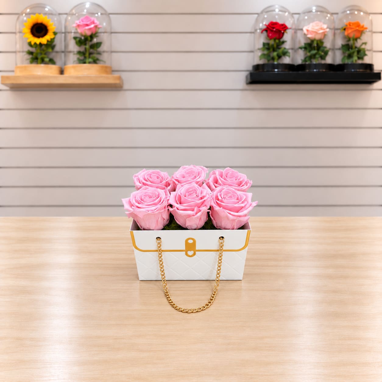 Pink roses in a white handbag-style box with a gold chain handle
