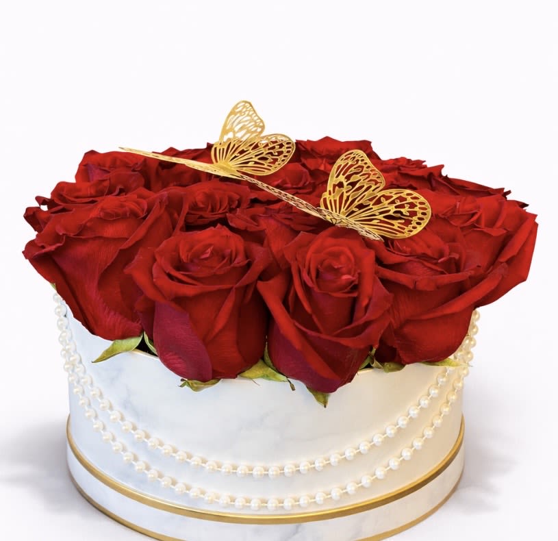 Round box of red roses topped with gold butterfly decorations