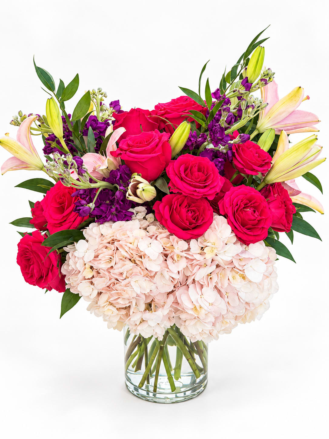 Bouquet of hot pink roses, pale hydrangeas, and lilies in a glass vase