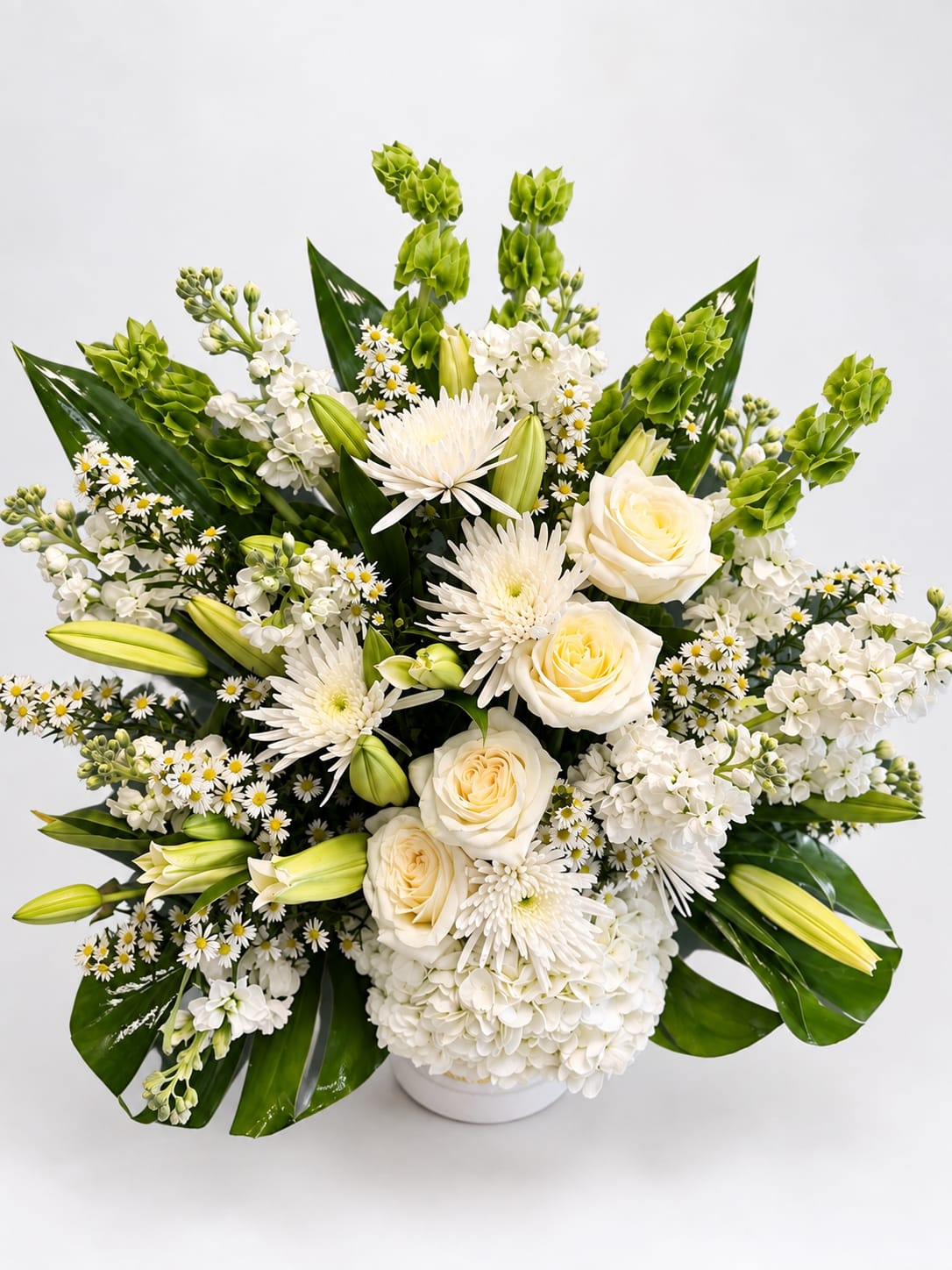 White floral arrangement with roses, lilies, and chrysanthemums in a white vase