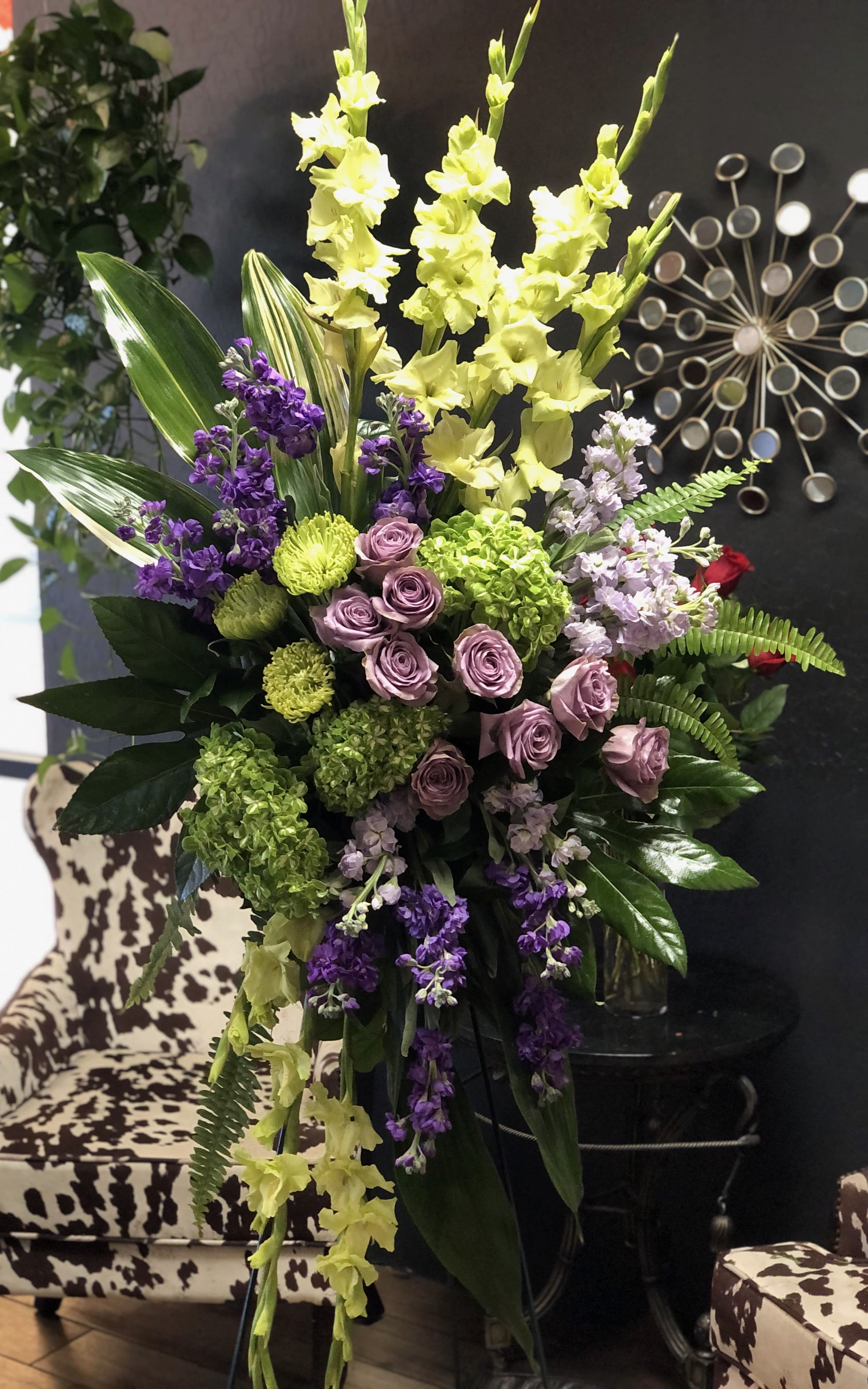 Tall floral arrangement with yellow gladiolus, purple flowers, and pink roses