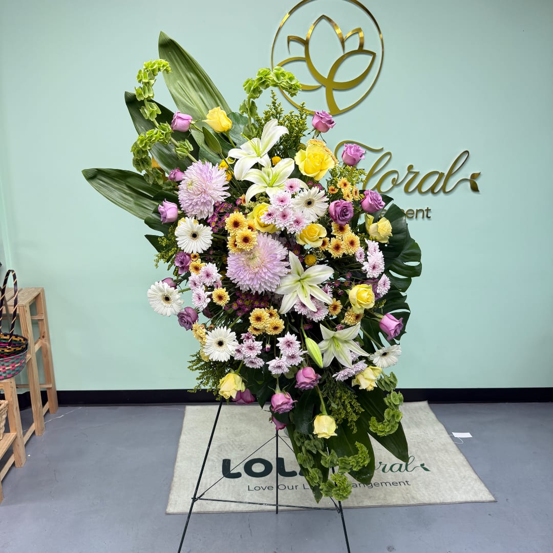 Large standing floral arrangement with lilies, roses, and daisies