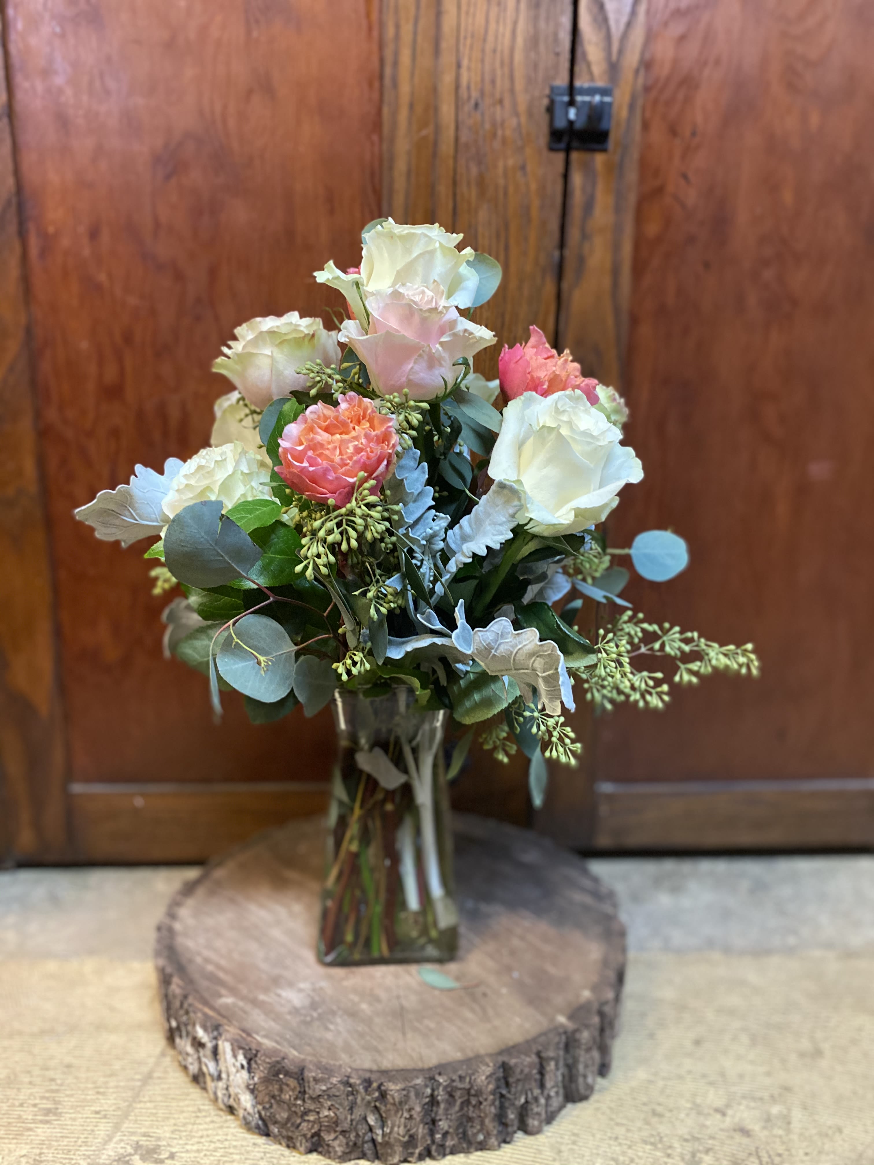 Bouquet of pale roses and coral blooms in a glass vase