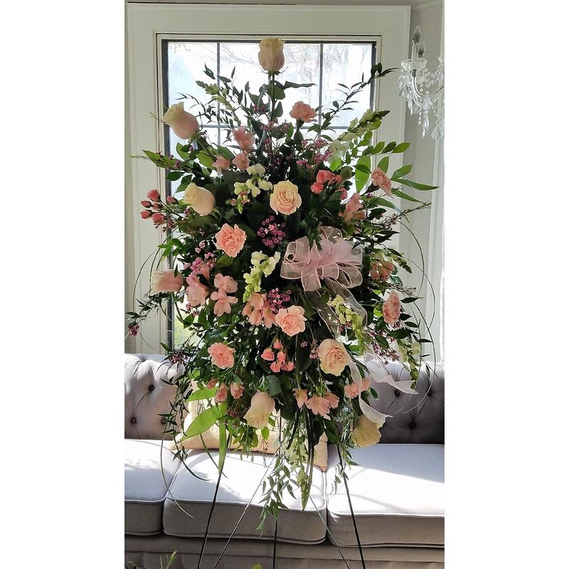 Tall pink and cream floral arrangement on a stand with a ribbon bow