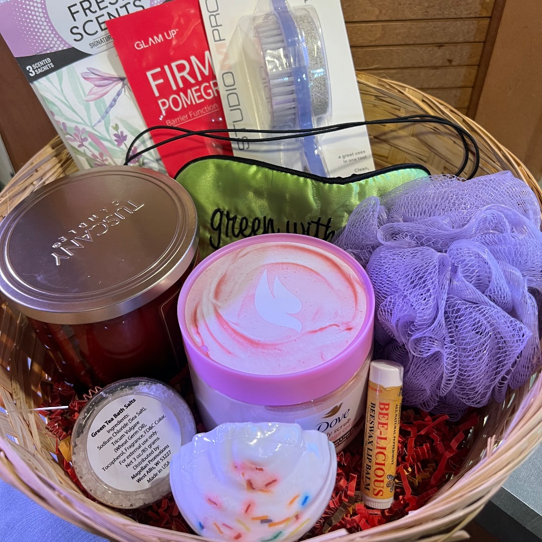 Basket of bath and body gifts with candles, scrub, lip balm, and a loofah