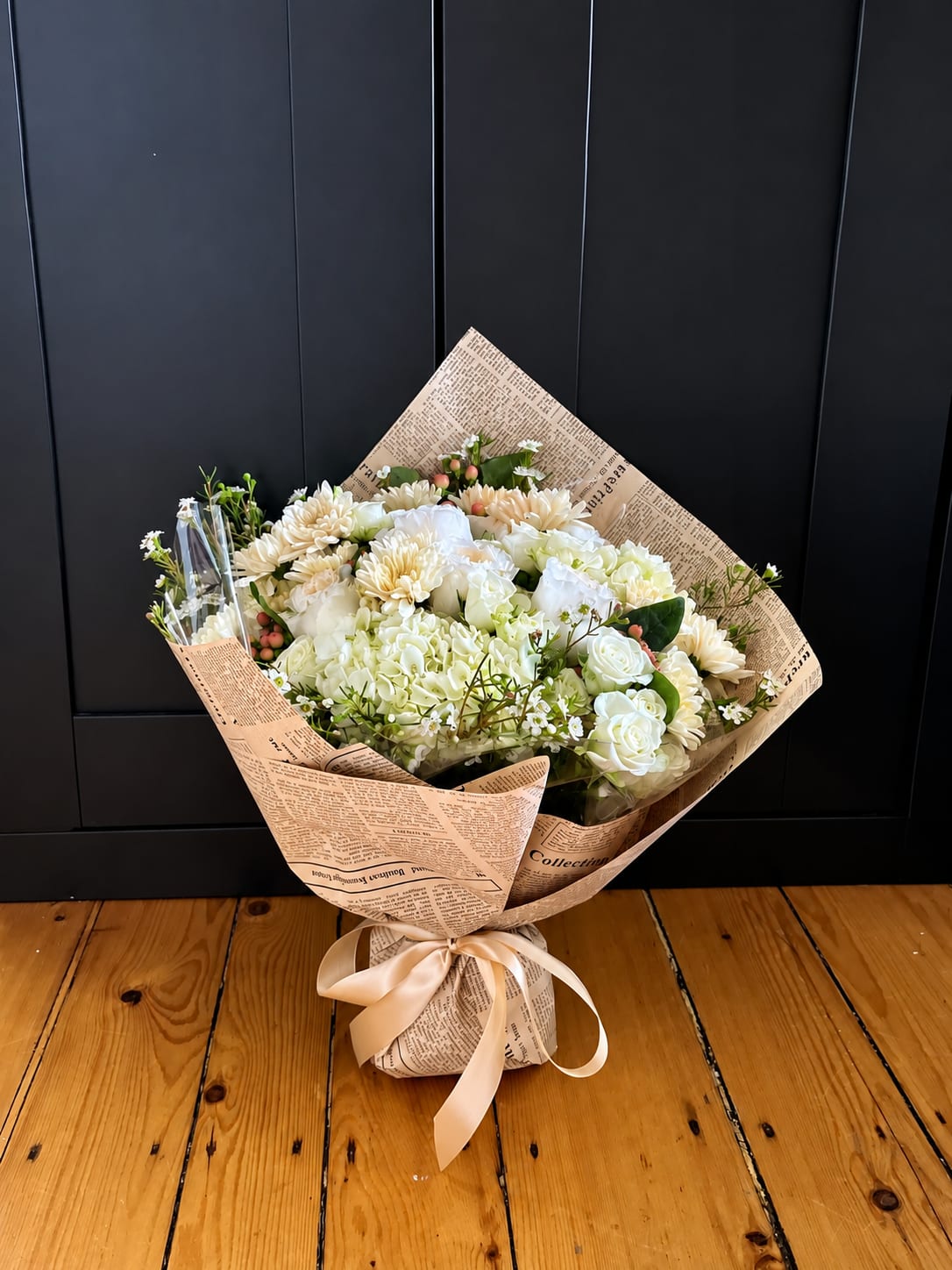 Wrapped bouquet of white and cream flowers tied with a satin ribbon