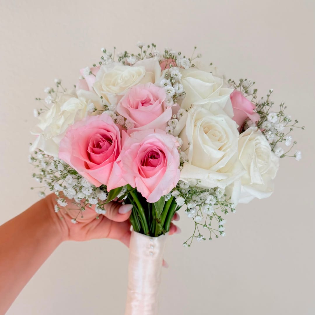 Handheld bouquet of pink and white roses with baby's breath