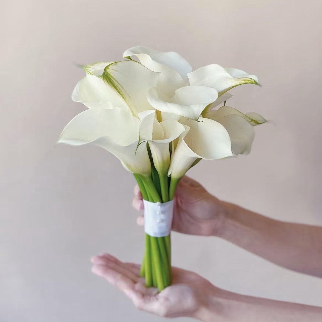 Handheld bouquet of white calla lilies with a white wrap