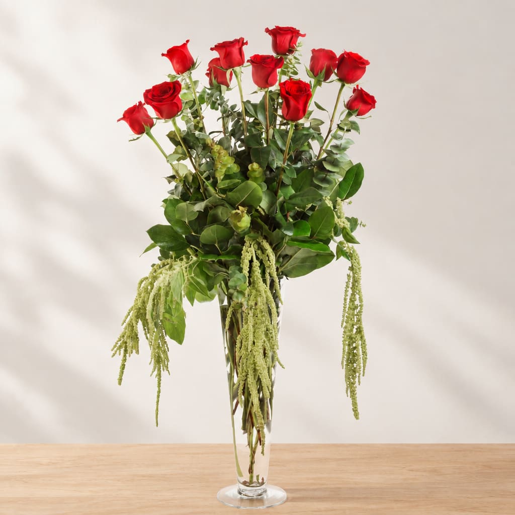 Tall vase arrangement of red roses with cascading greenery