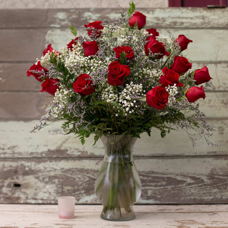 Red roses arranged in a clear glass vase with baby's breath