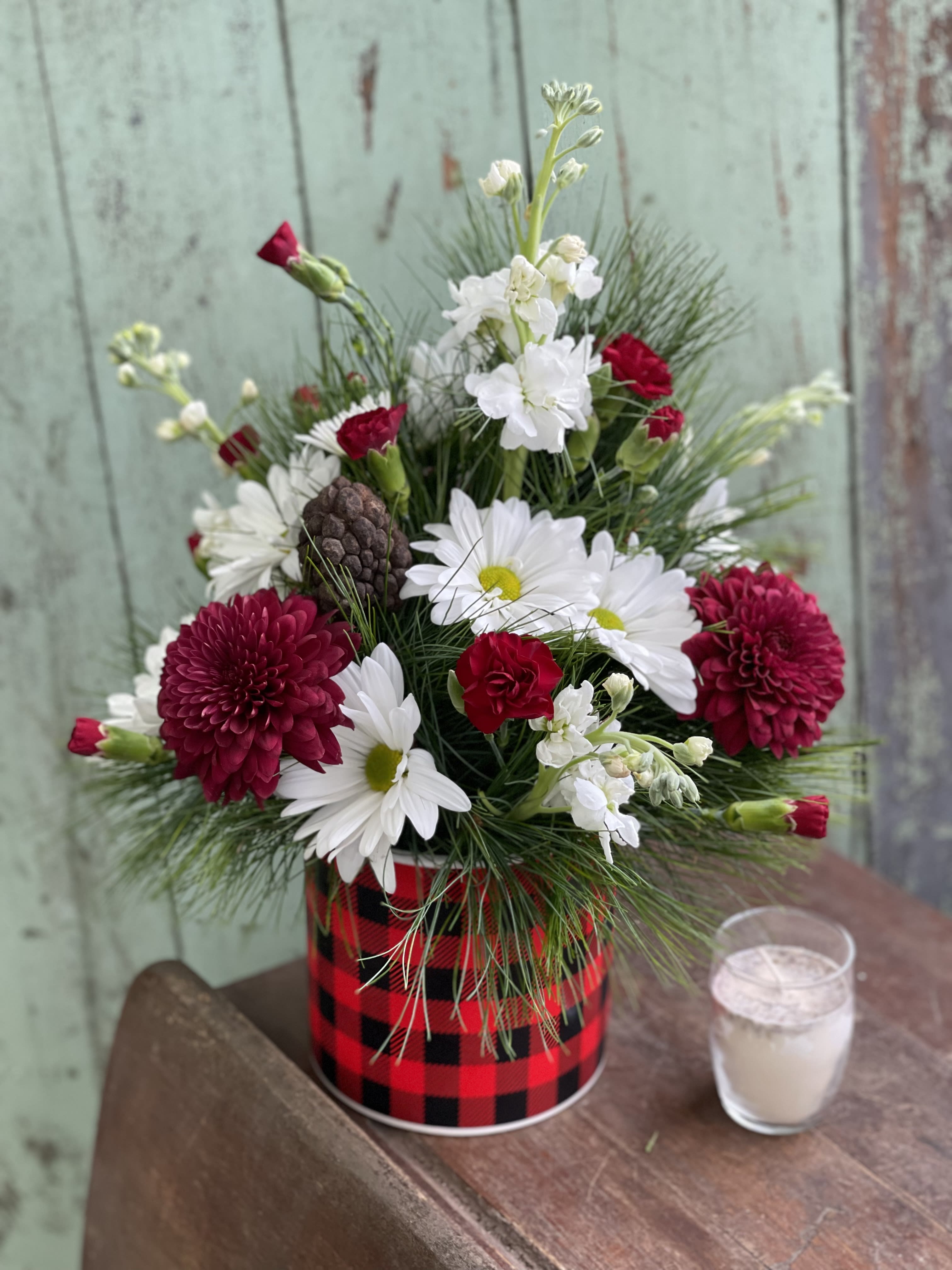 Red and white flower arrangement in a plaid tin container