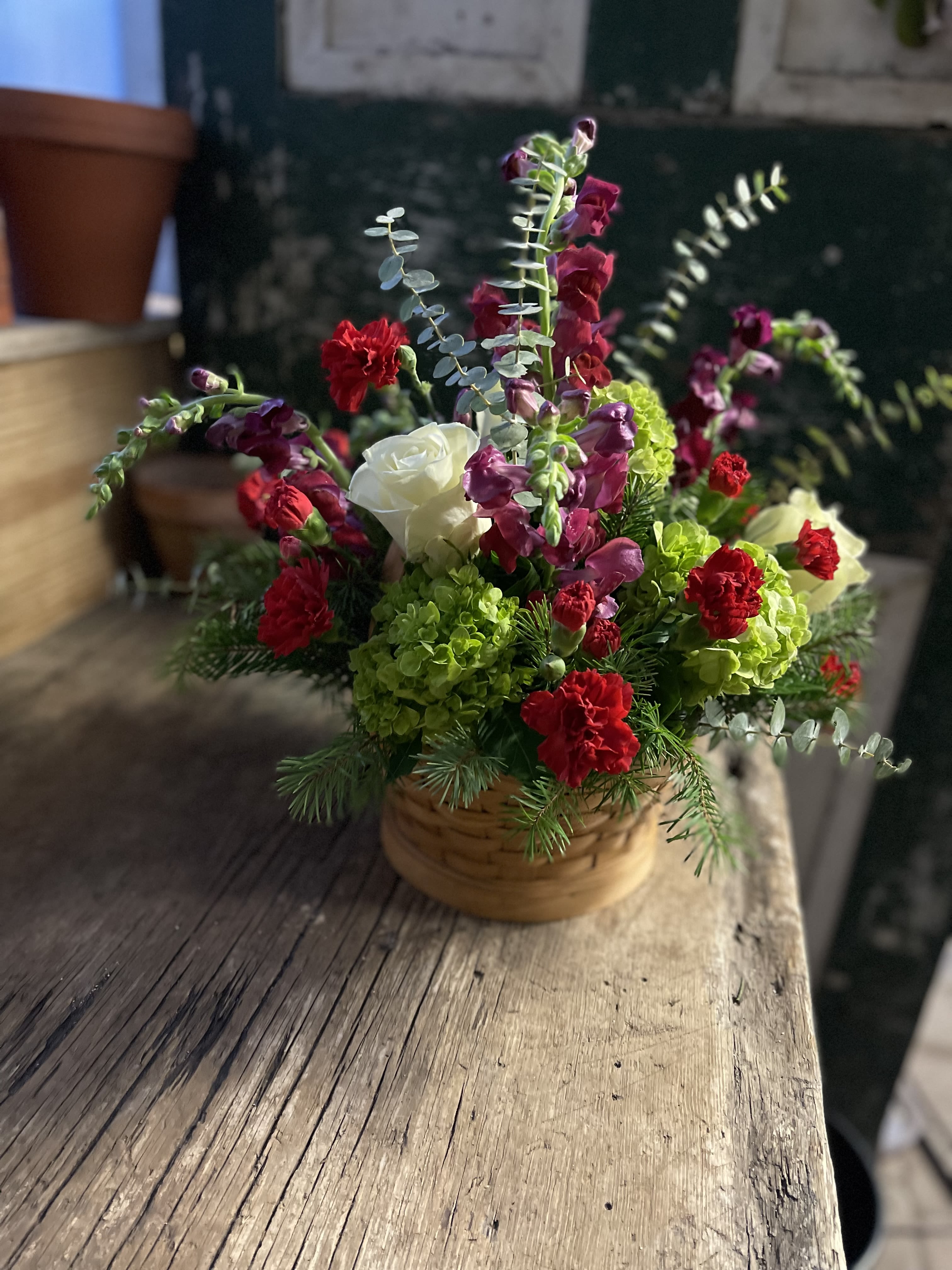 Basket arrangement with red and white flowers and green blooms