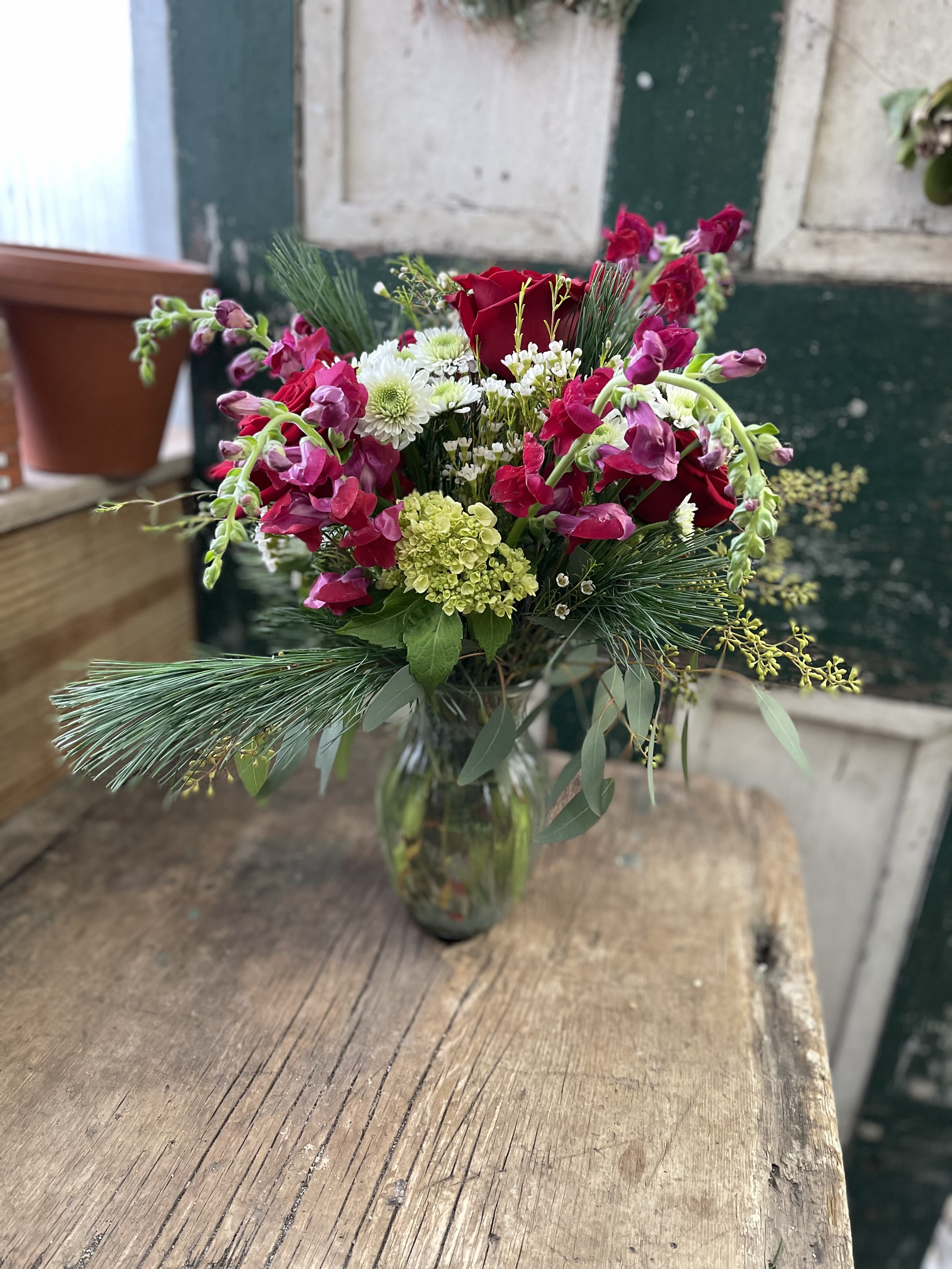 Bouquet of red roses and pink snapdragons in a glass vase