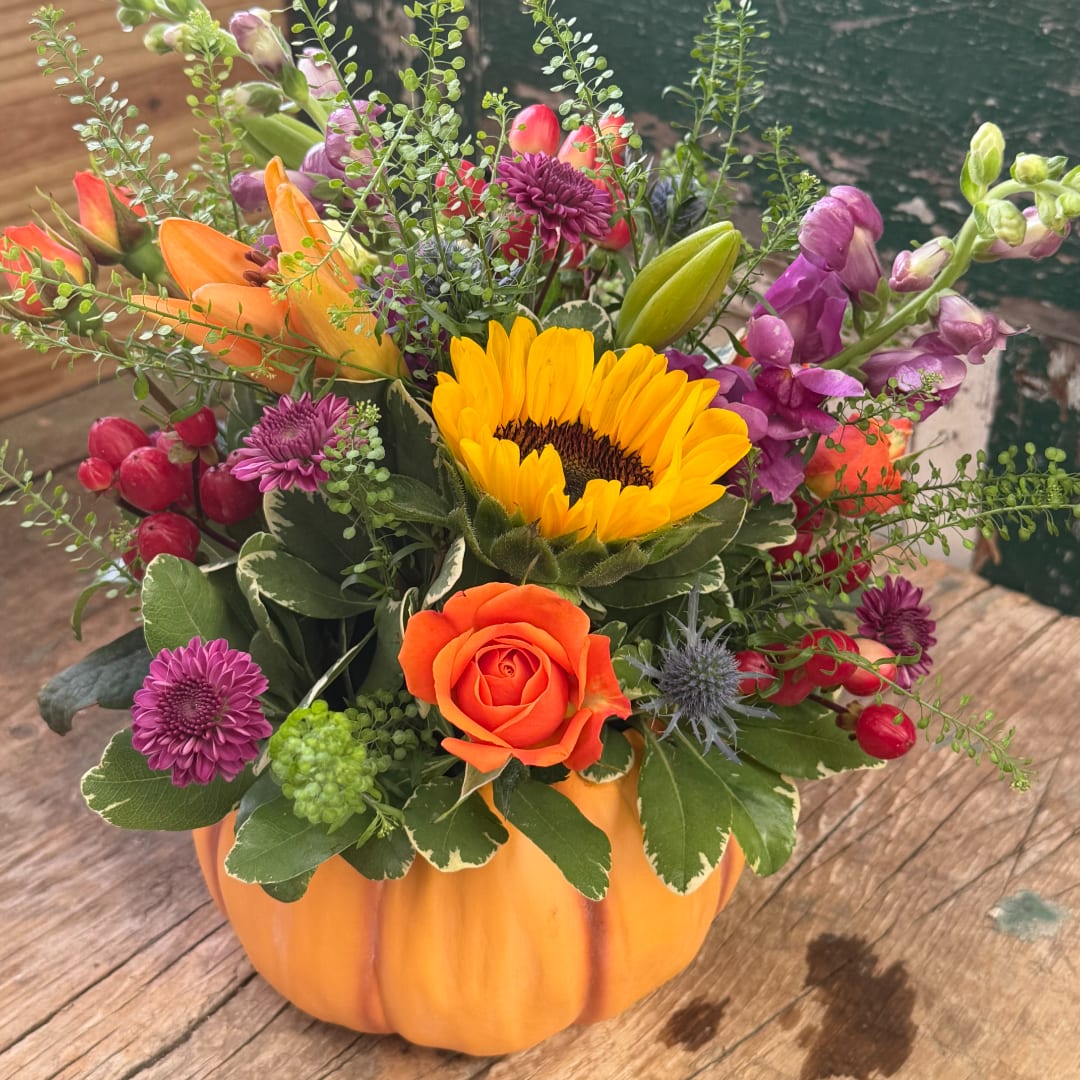 Mixed bouquet in a pumpkin-shaped container with a sunflower and orange rose