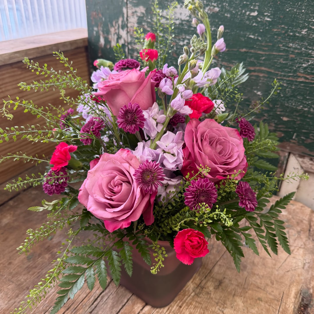 Pink roses and purple flowers arranged in a vase