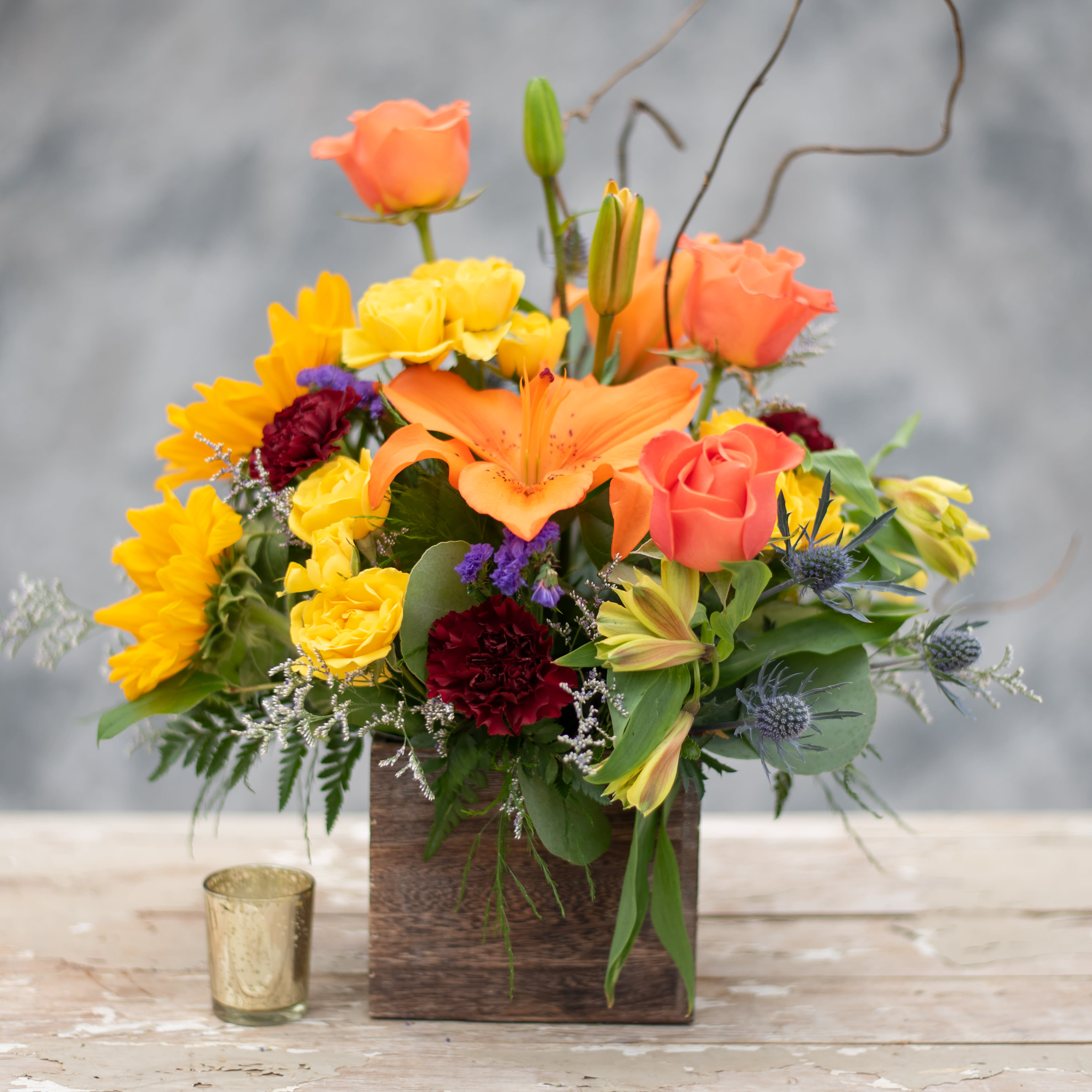 Colorful mixed flower arrangement in a wooden box with roses and lilies