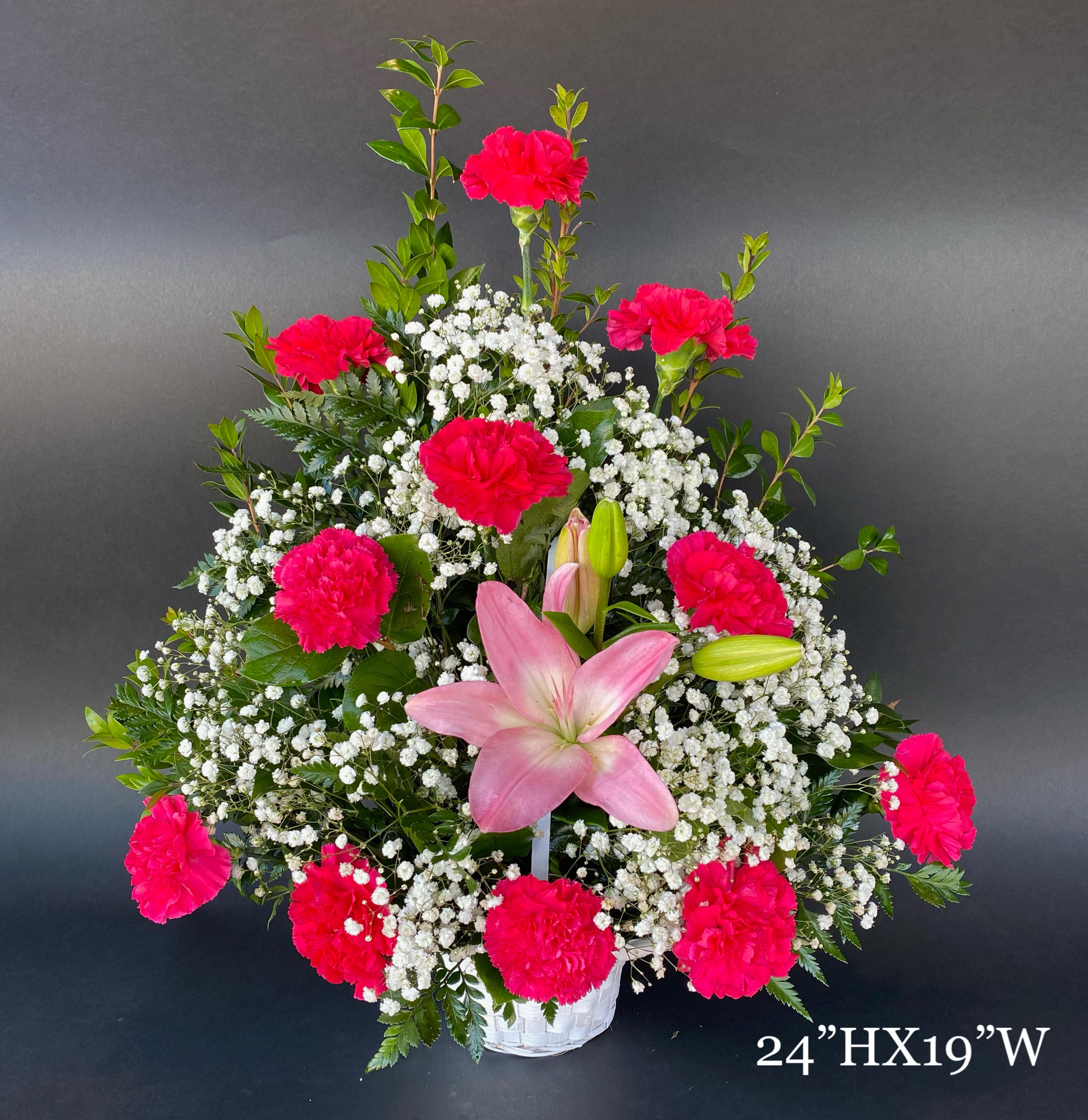 Pink lilies and carnations in a white basket with baby's breath