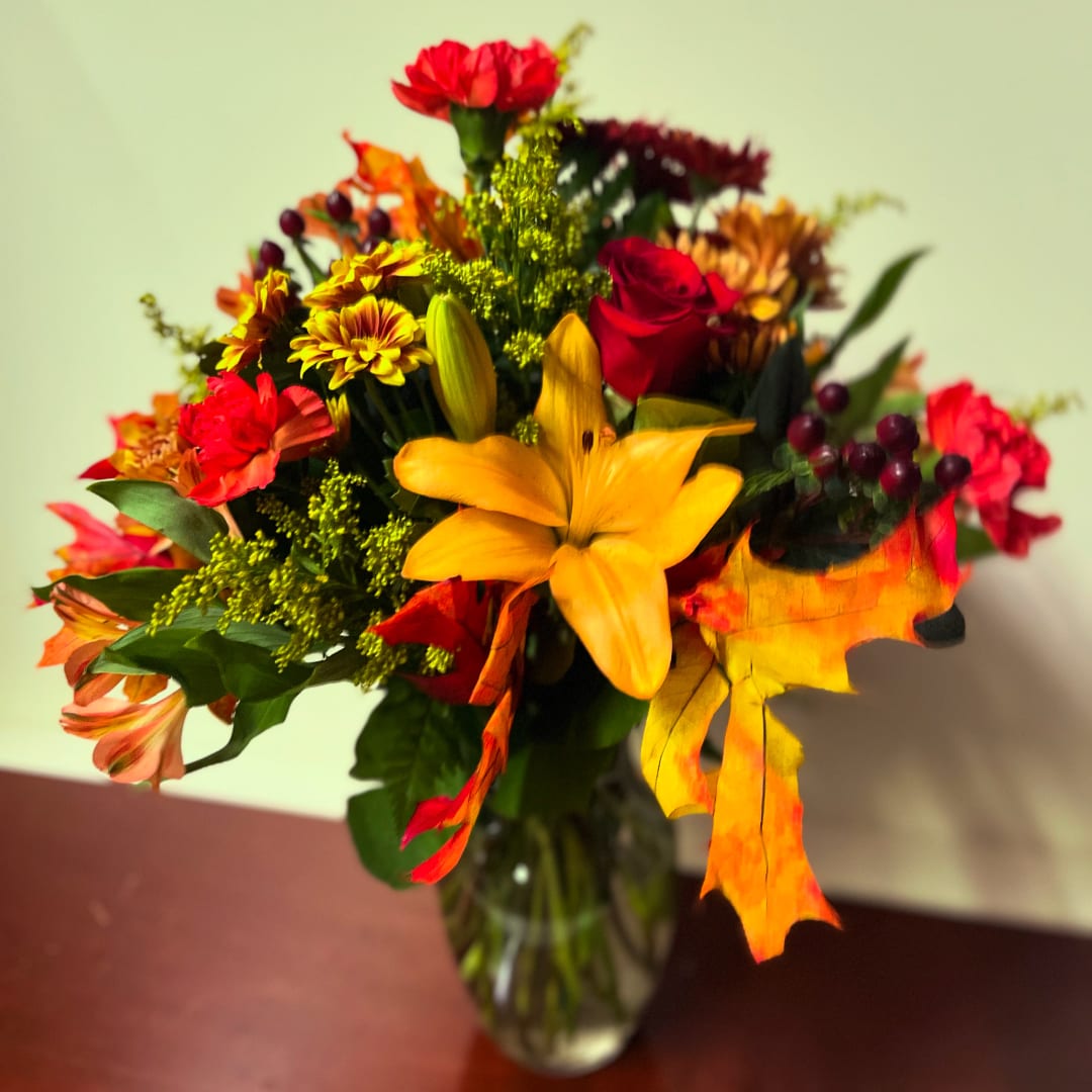 Mixed bouquet of red, yellow, and orange flowers in a glass vase