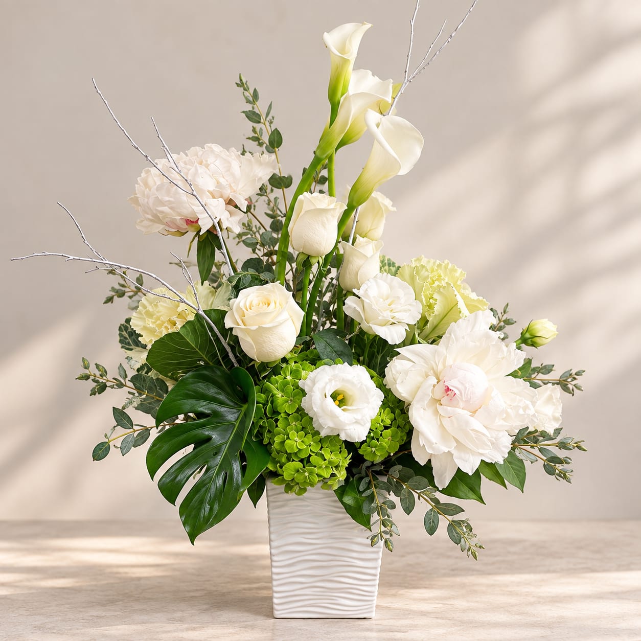 White floral arrangement in a textured white vase with calla lilies and roses