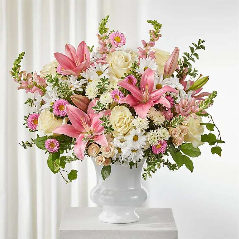 Empathetic Blooms Urn Arrangement - Filled with soft, blushing blooms, the Empathetic Blooms Urn Arrangement creates a graceful and comforting display, perfect for a service or as a thoughtful piece for the home. The Deluxe Bouquet measures approximately 22" H x 23" W. It is professionally arranged by florists and arrives ready for display. For longer-lasting blooms, add water daily. Pet Safety Note: Some flowers and greenery in this arrangement may be toxic to pets, so please keep it out of their reach to ensure their safety.