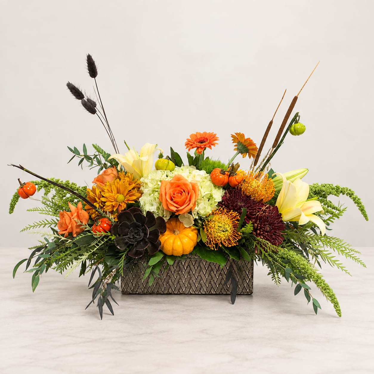 Autumn floral arrangement in a rectangular vase with orange, yellow, and dark blooms