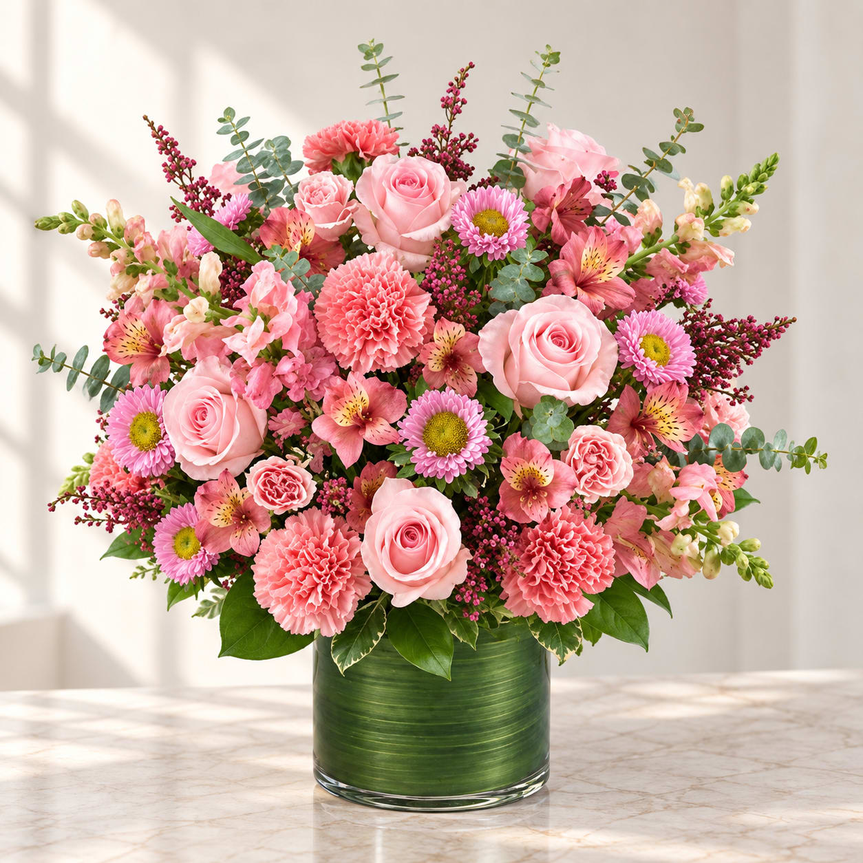 Pink mixed flower arrangement in a green glass vase