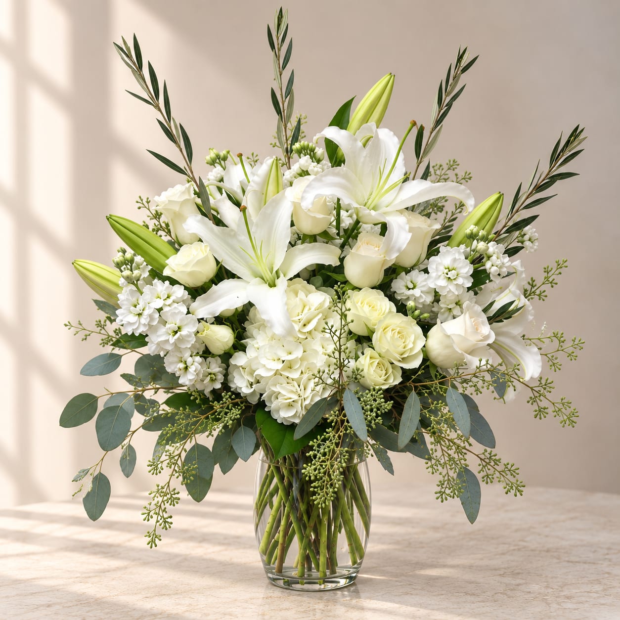 White lilies and roses arranged in a clear glass vase