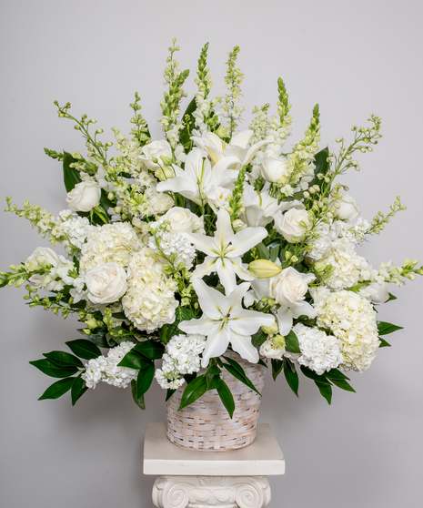 White lilies and roses in a woven basket arrangement