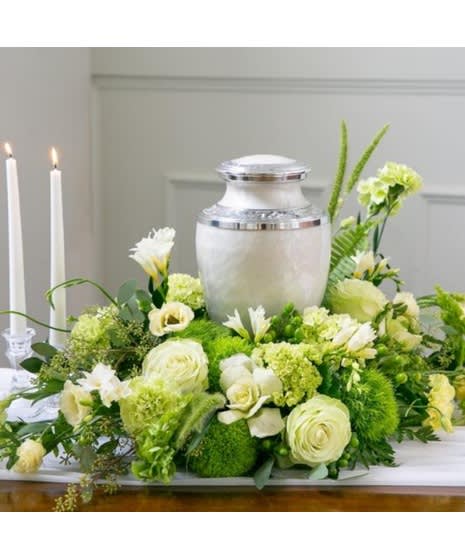 Green and white funeral floral arrangement with an urn centerpiece