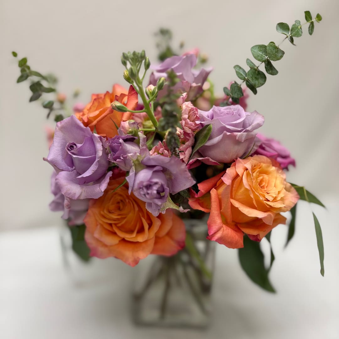 Bouquet of lavender and orange roses in a clear vase