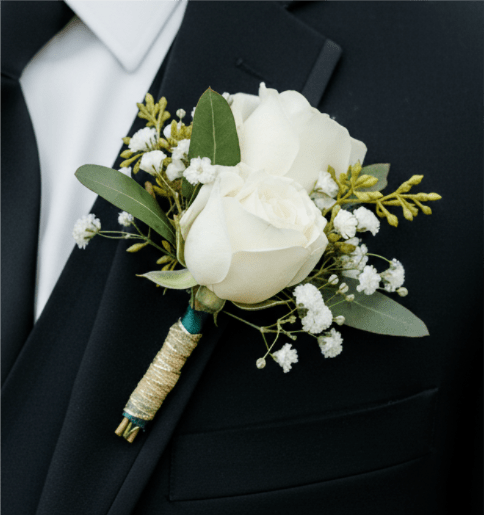 White rose boutonniere with small white filler flowers on a black suit lapel