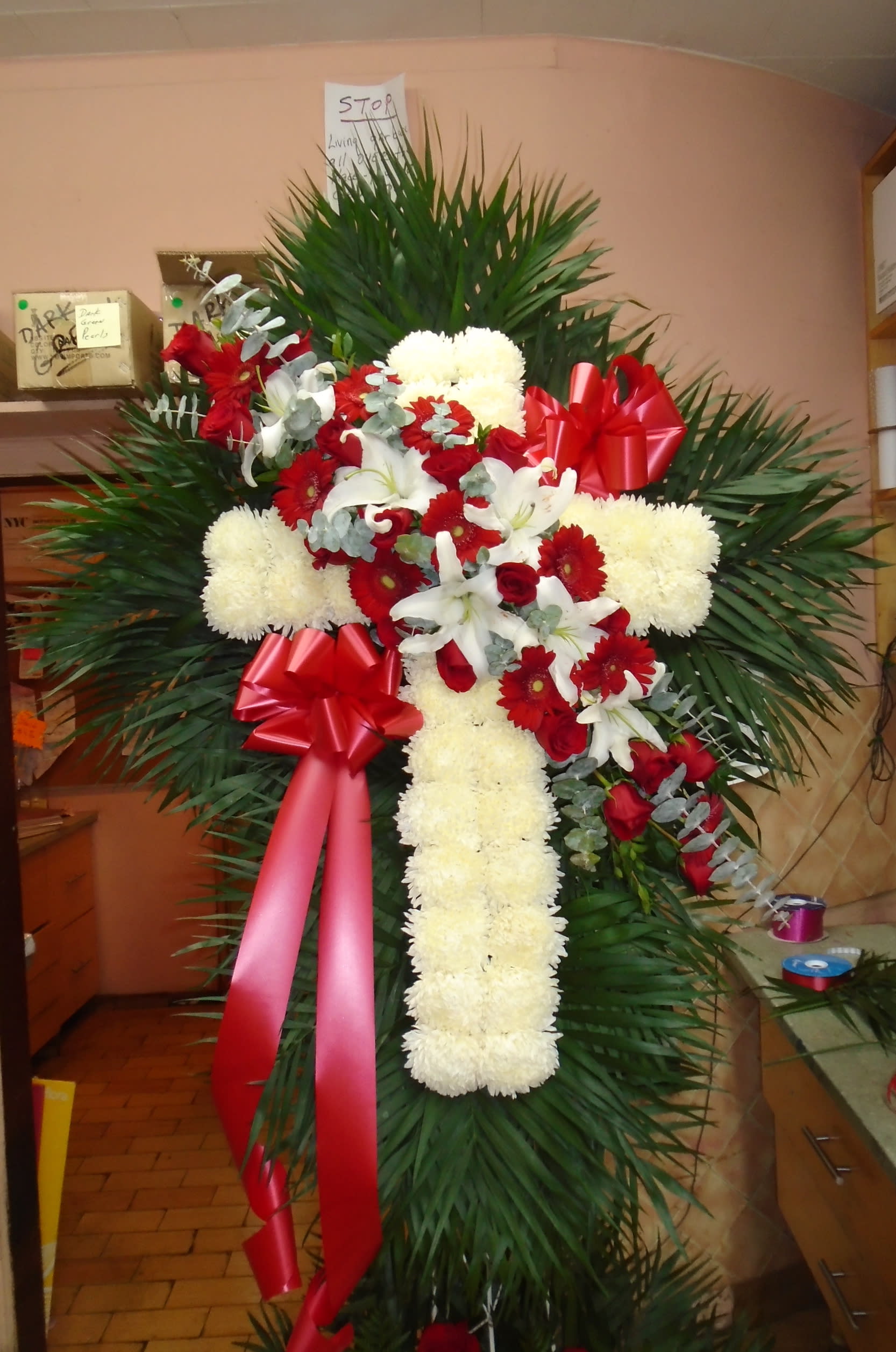 Standing floral cross with red and white flowers and red ribbons