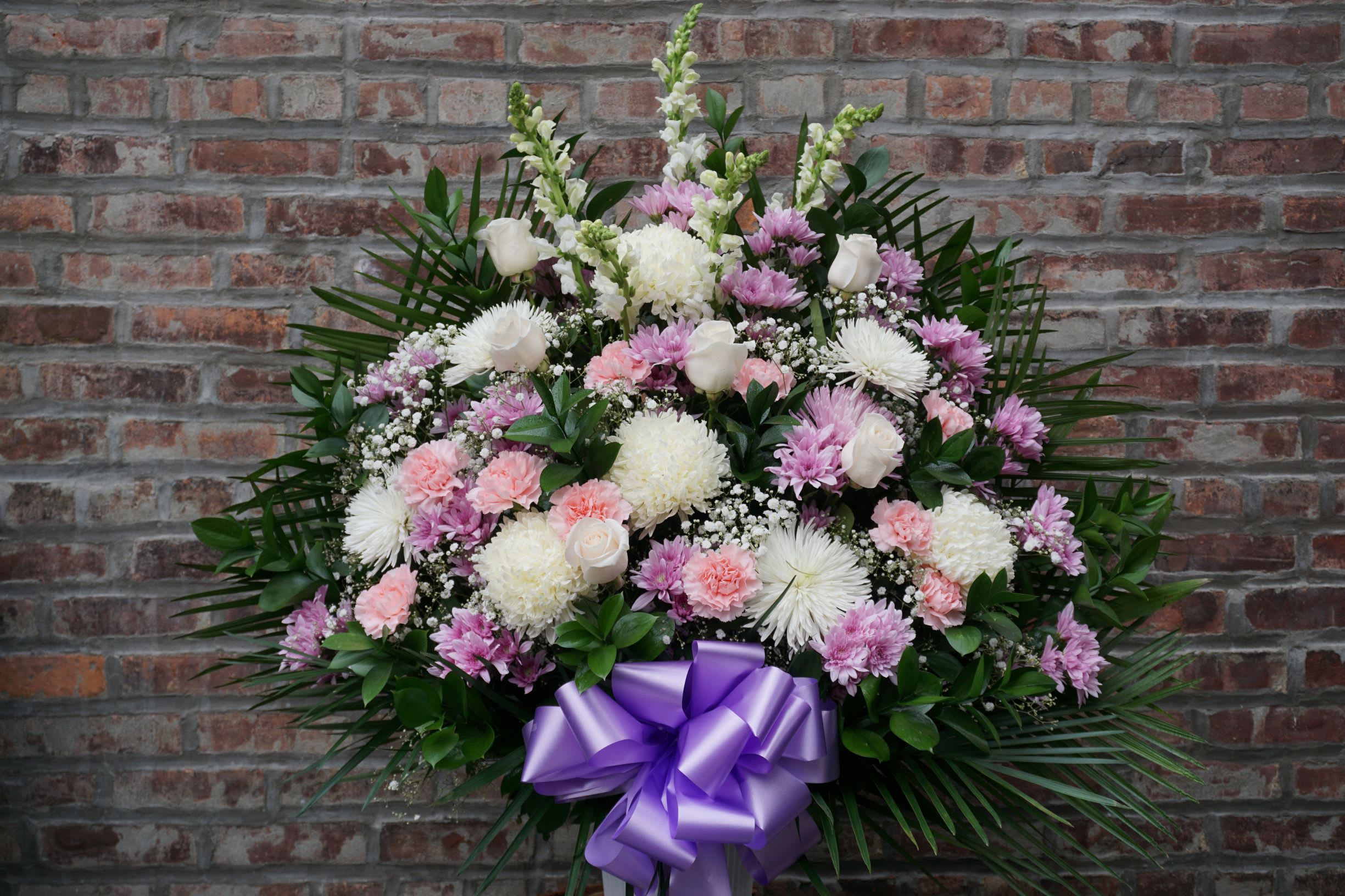 Large pink and white floral spray with a purple ribbon bow