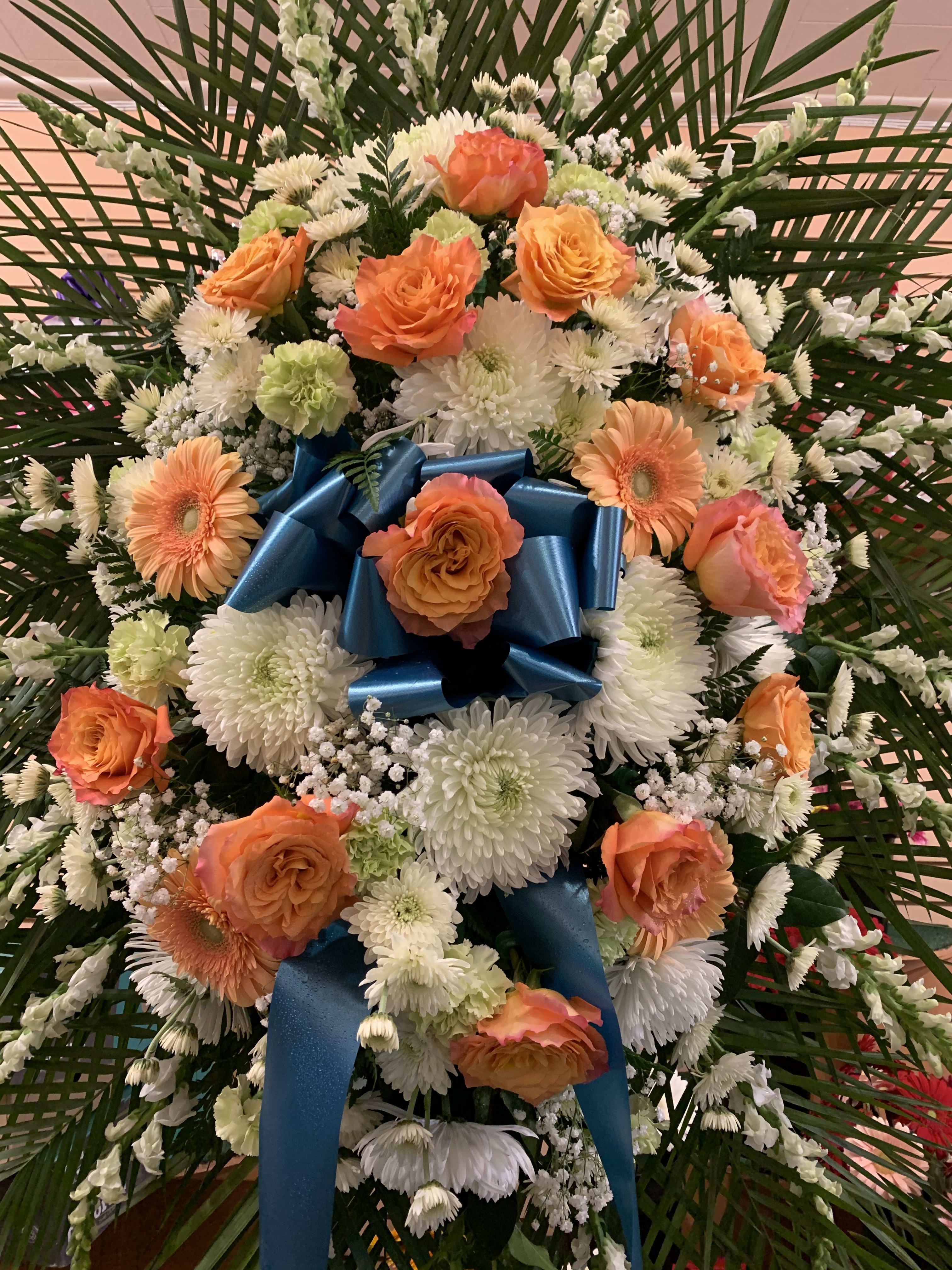 Orange roses and white daisies arranged with a blue ribbon bow