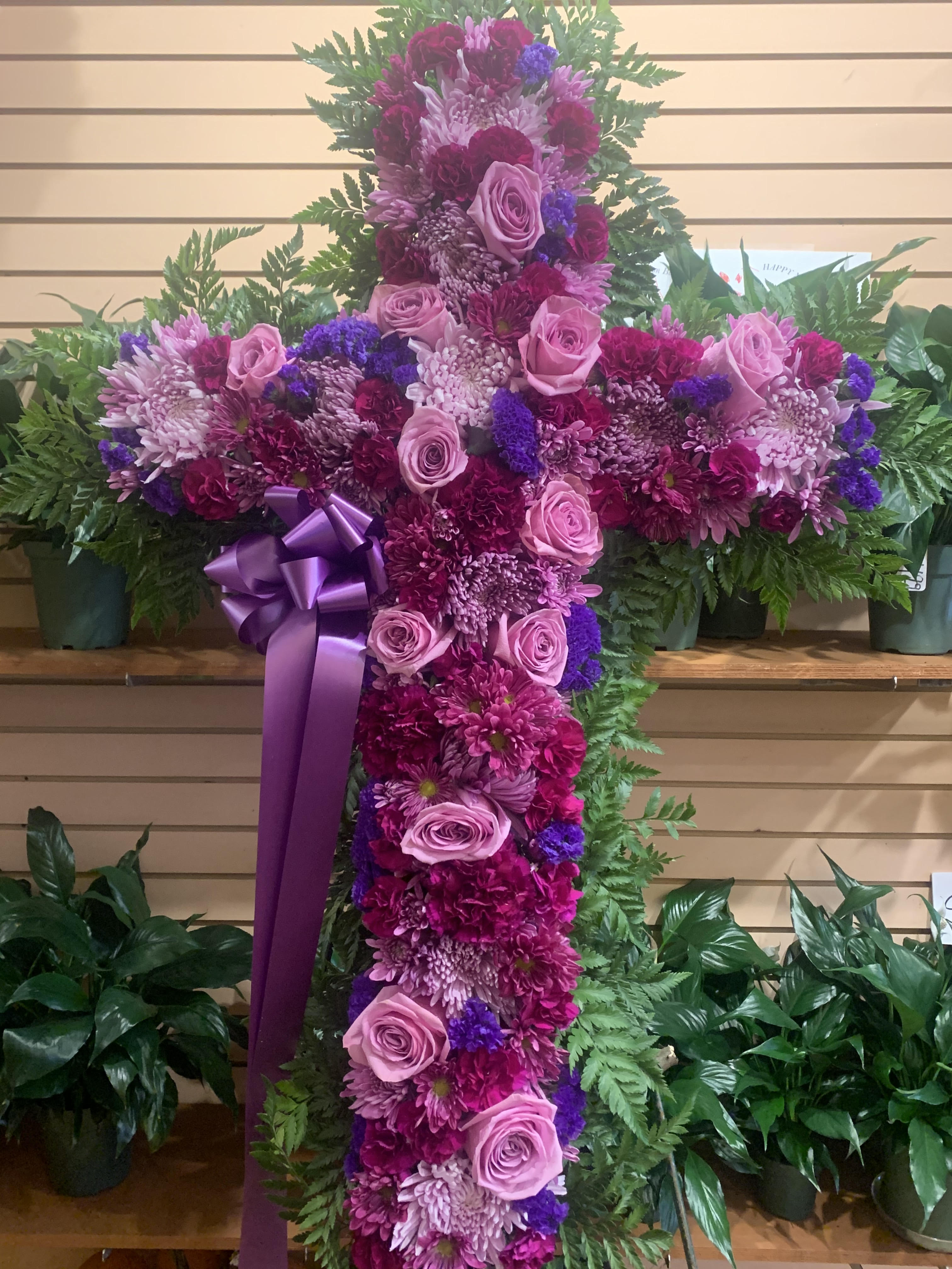 Large floral cross with pink and purple flowers and a ribbon bow