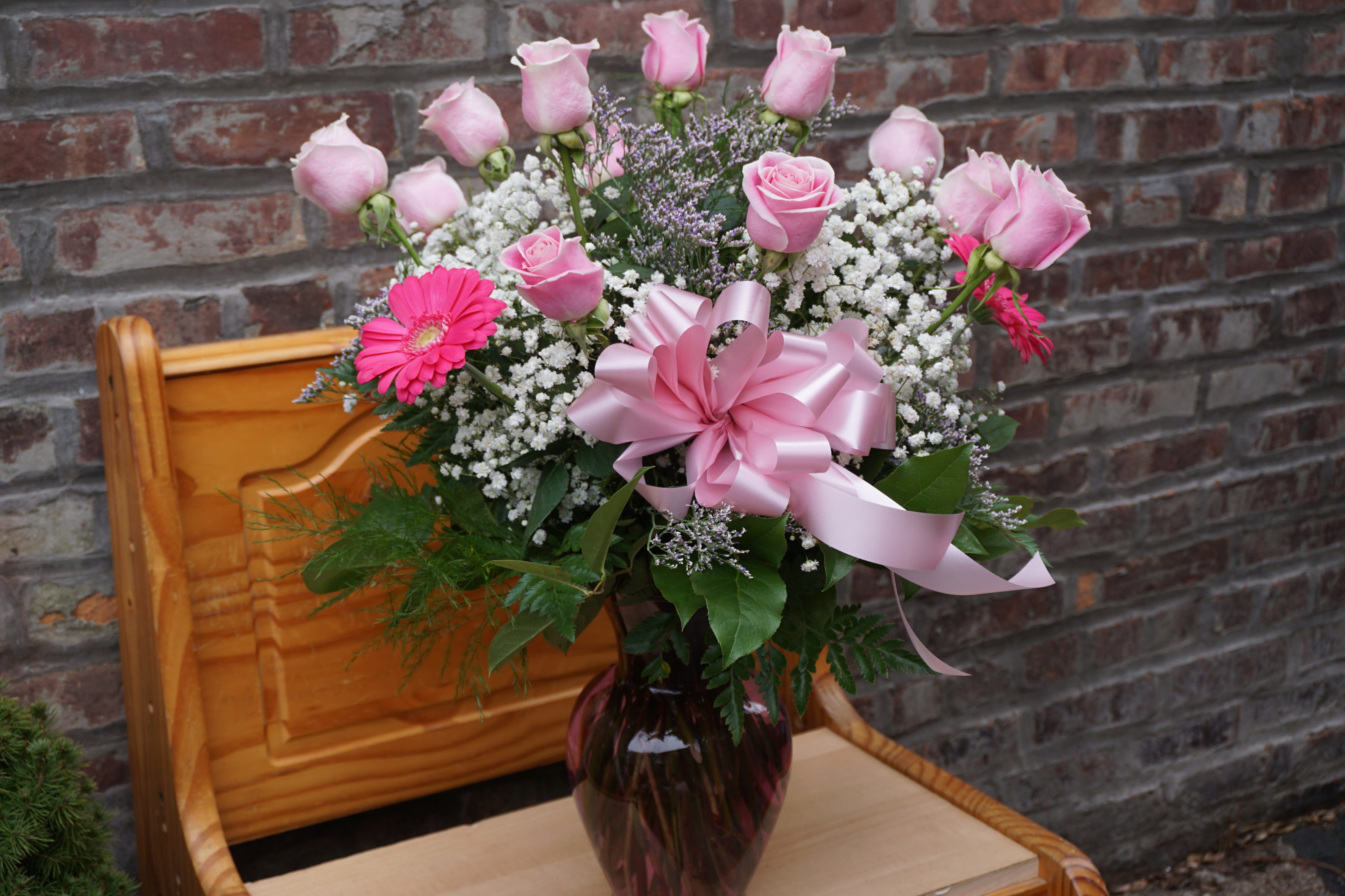 Pink roses and gerbera daisies in a vase with a pink ribbon