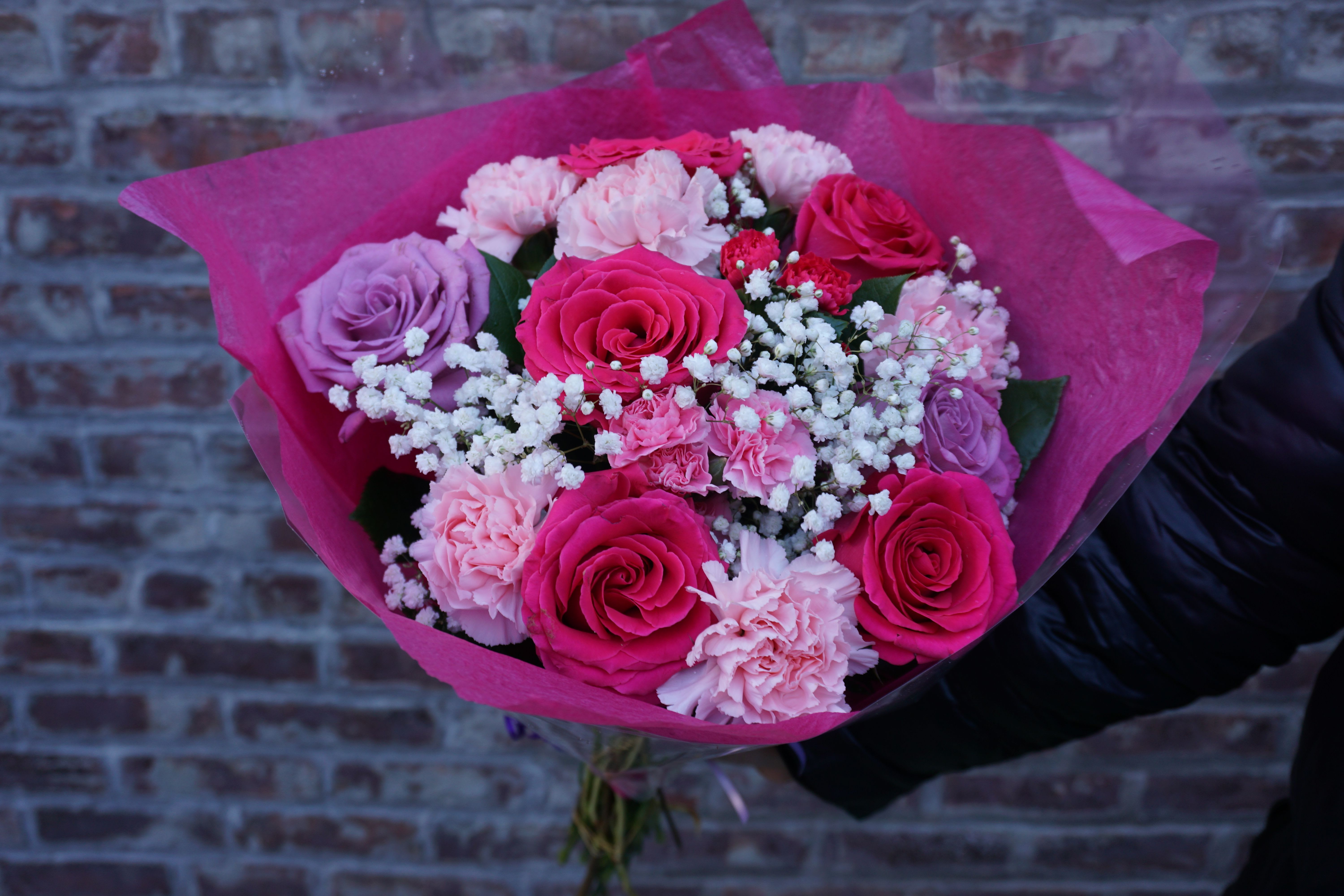 Bouquet of pink and lavender roses with carnations in bright pink wrap