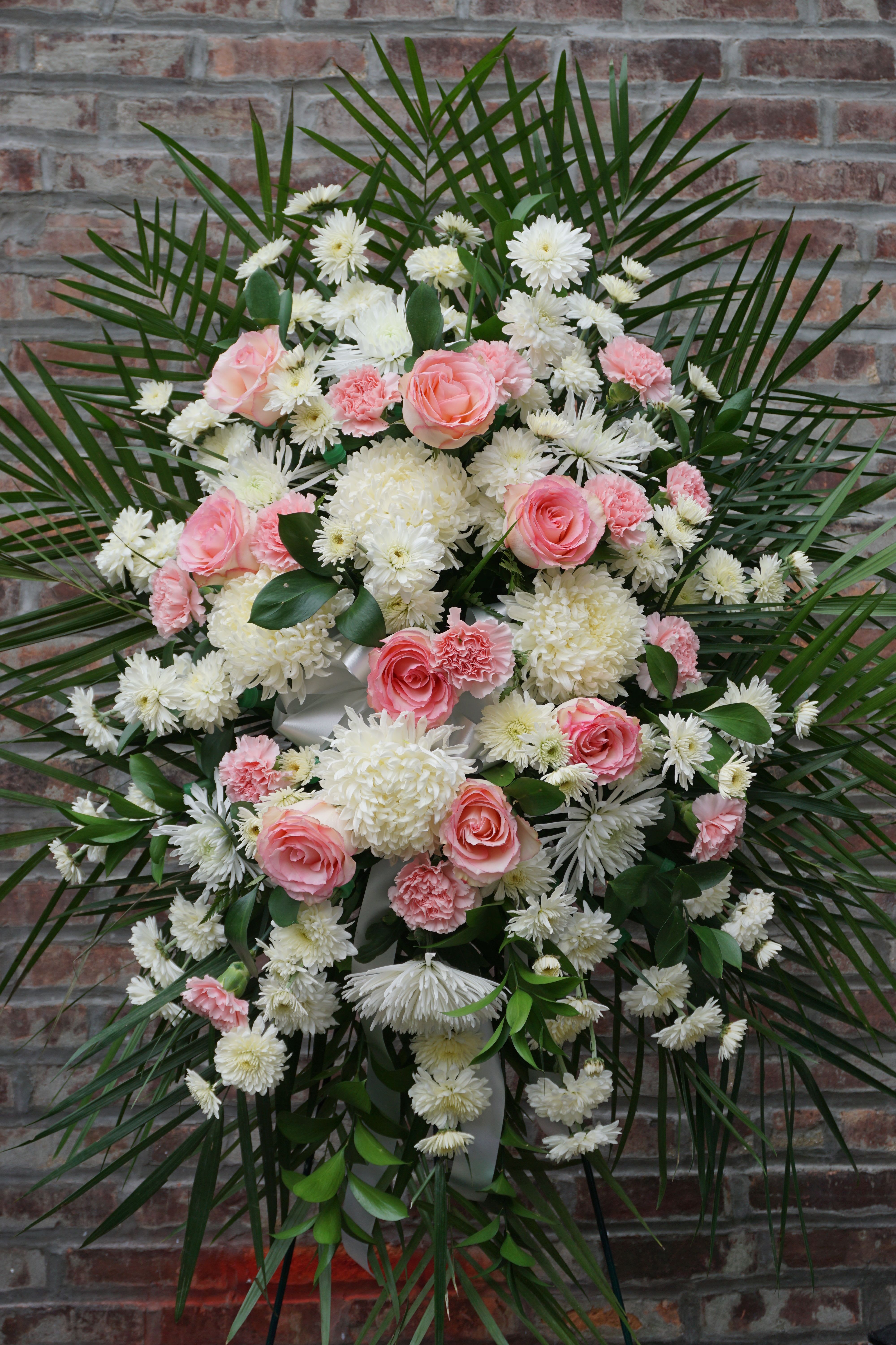 Pink roses and white chrysanthemums arranged in a large standing spray