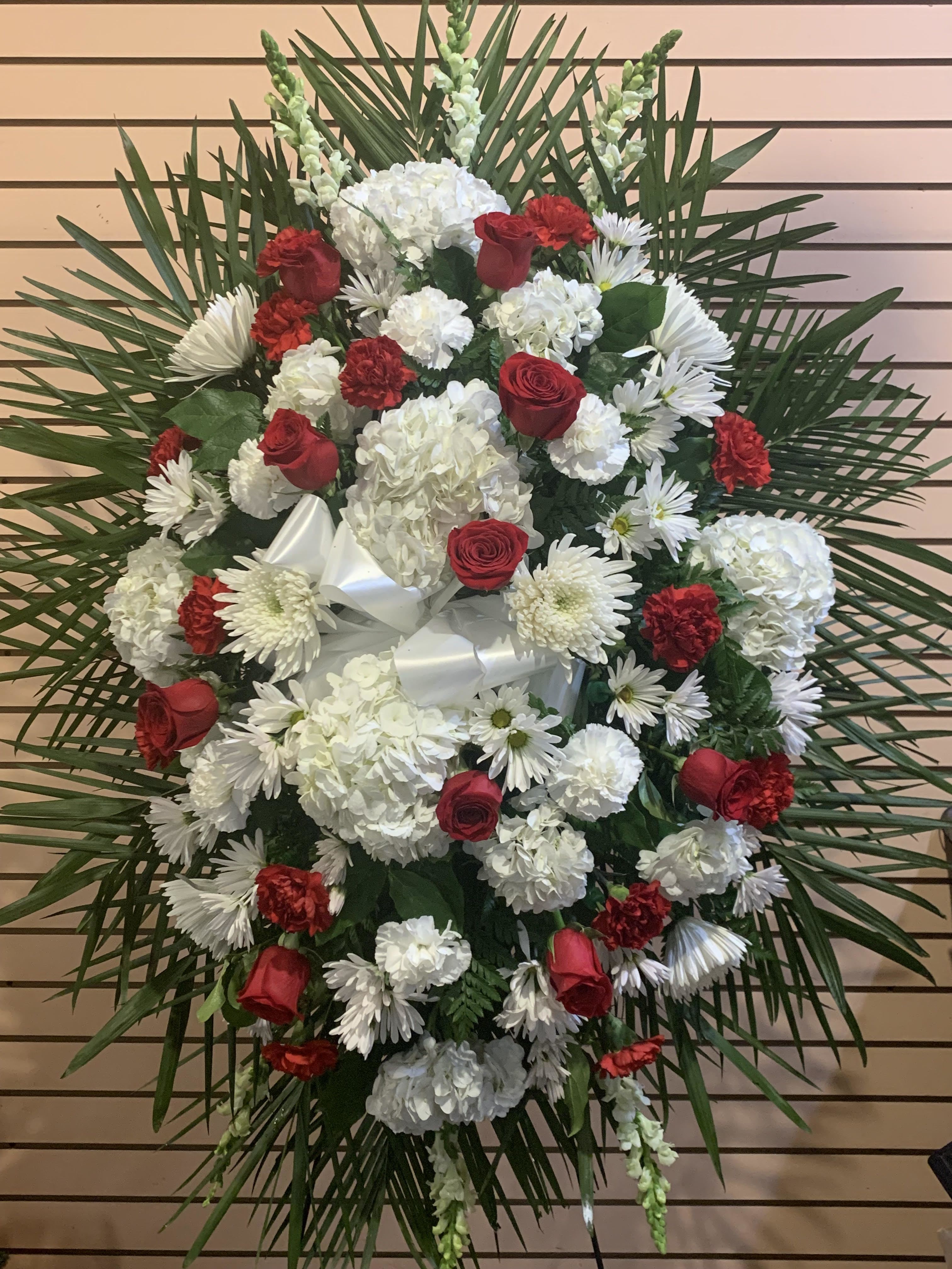 Standing floral spray with red roses and white flowers on a palm backdrop
